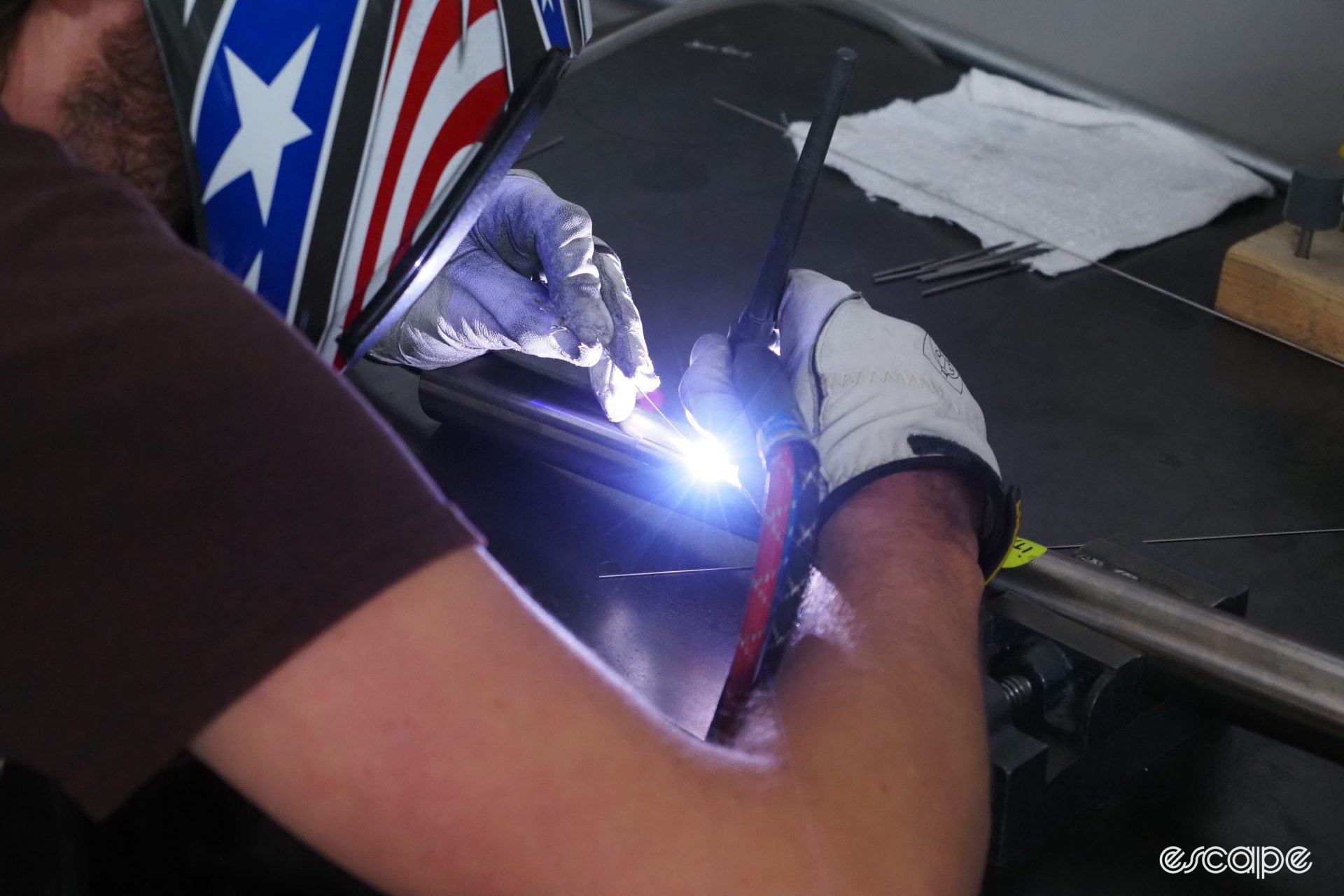 A welder fixes a titanium internal cable-guide tube inside a frame.
