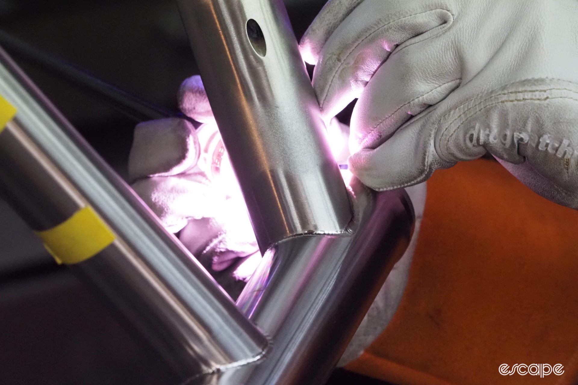 A closeup of a head tube weld, with the welding arc obscured by a tube, light from behind. 