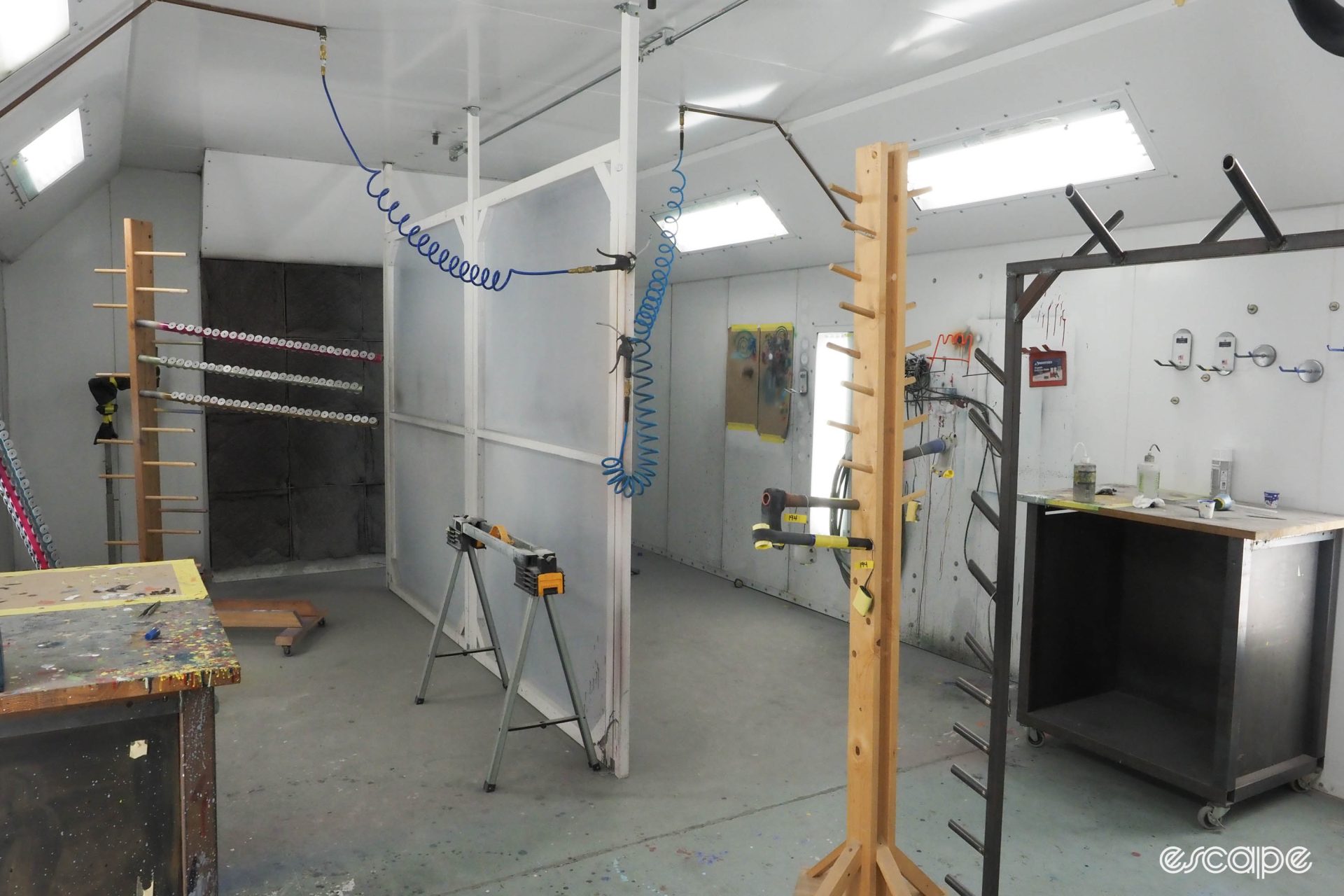 An empty paint booth with a frame "tree" and spray gun systems.