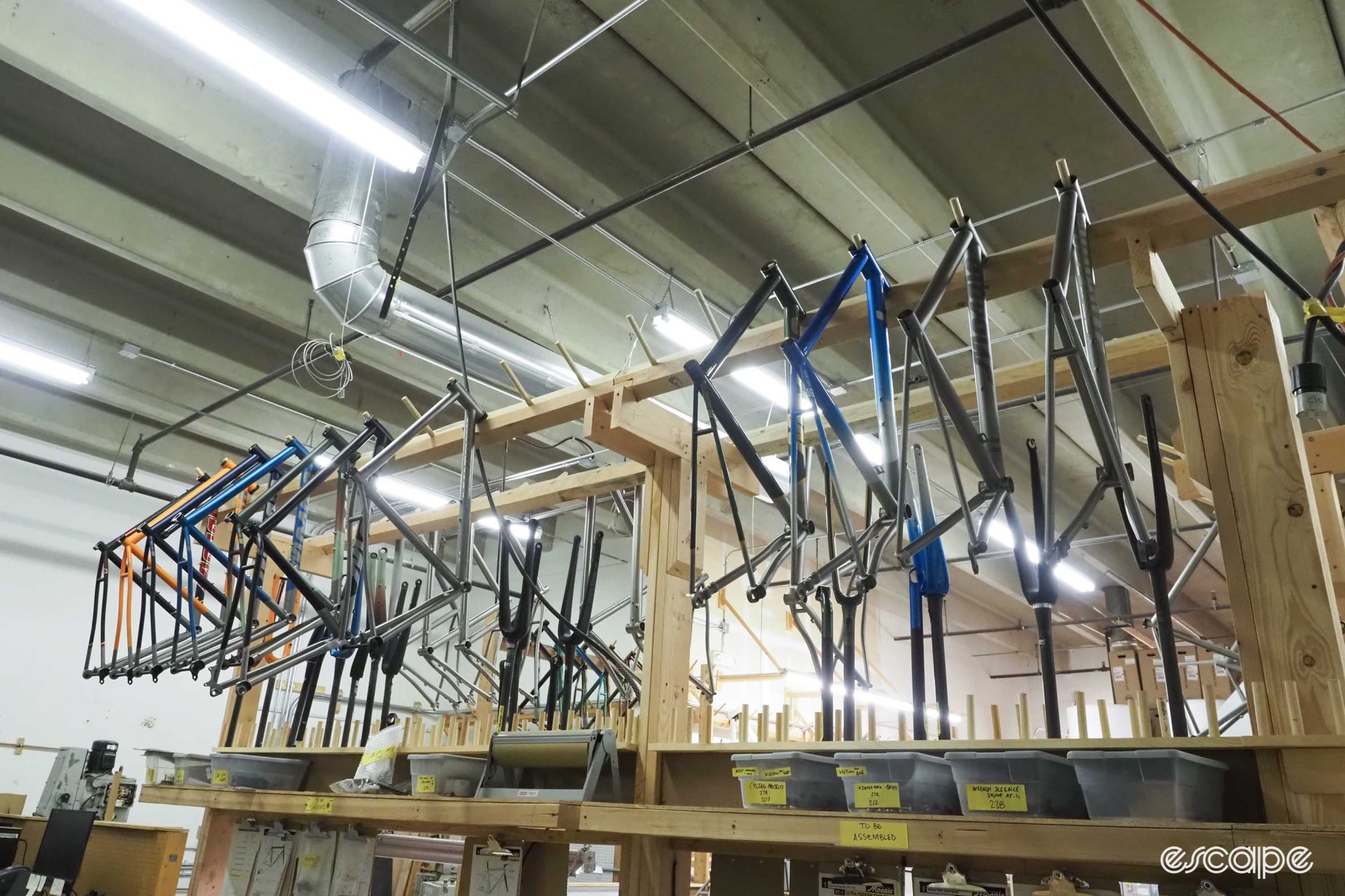 Rows of painted frames hang on a rack, ready to be boxed and shipped.
