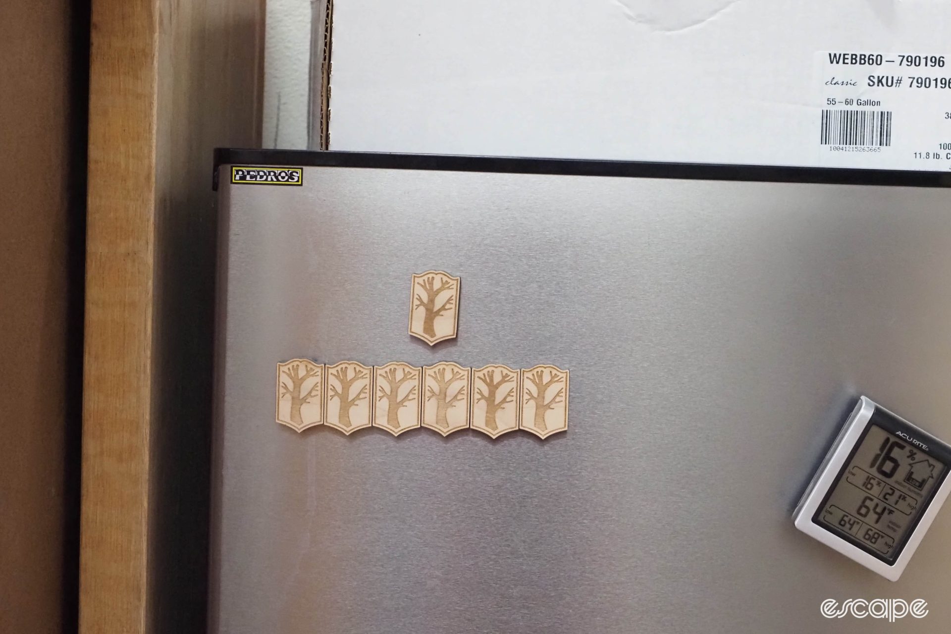 Magnets with the Mosaic logo are attached to a fridge. The logo is a tree trunk with multiple branches.