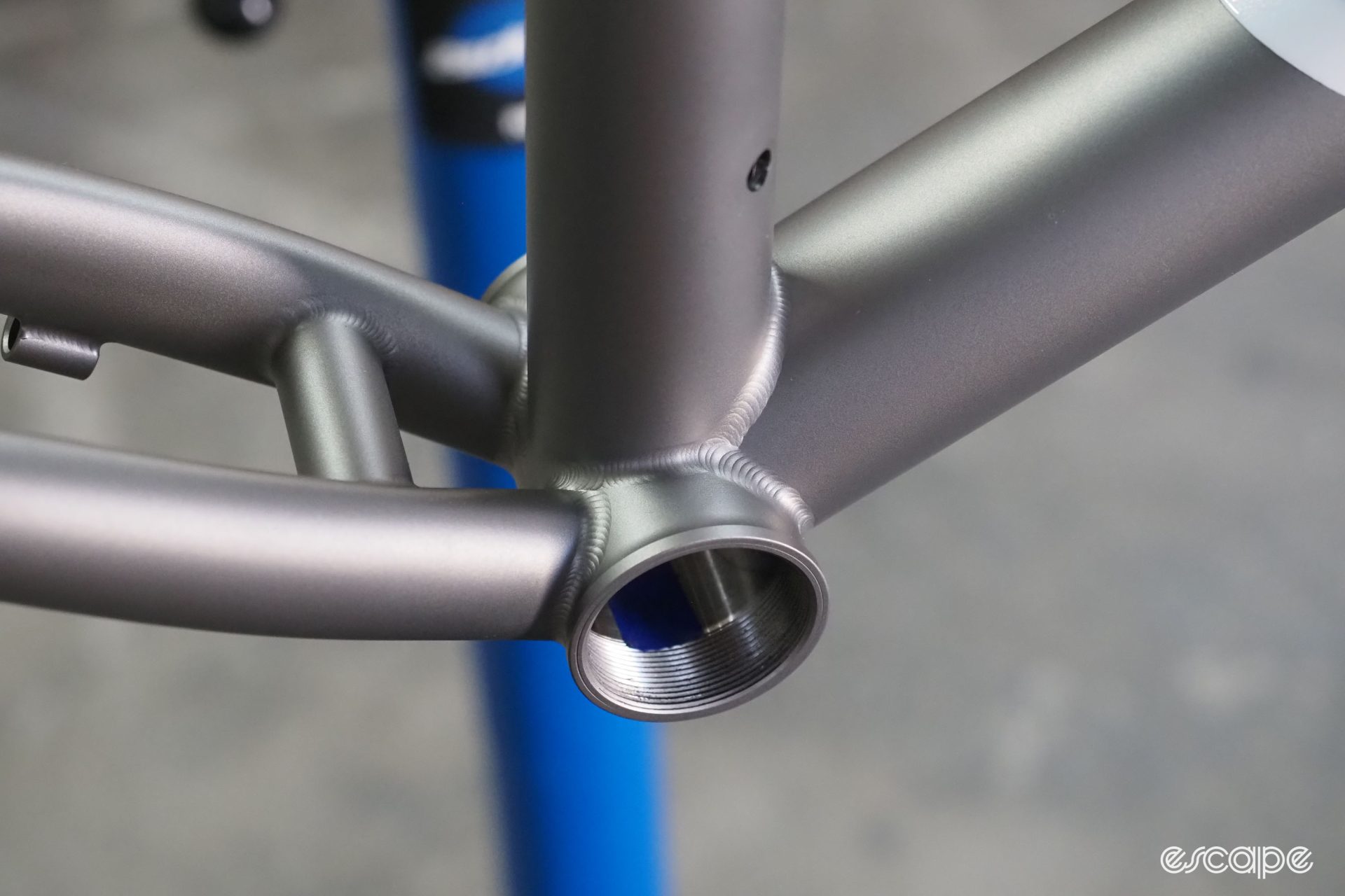 A closeup of a finished bottom bracket, with perfect TIG welds and a luscious bead-blasted raw finish.