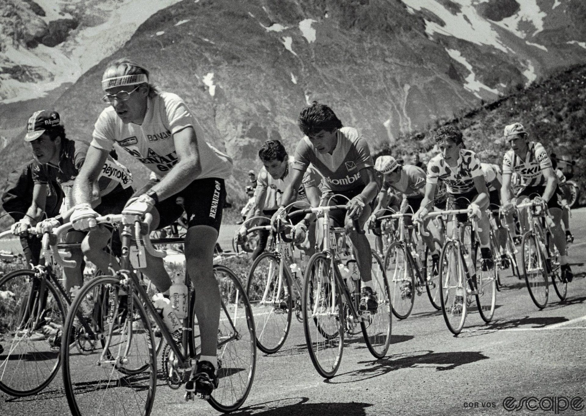 Laurent Fignon, in the yellow jersey, leads riders up a mountain pass in the 1984 Tour de France. He has his trademark headband on and his small, round eyeglasses.