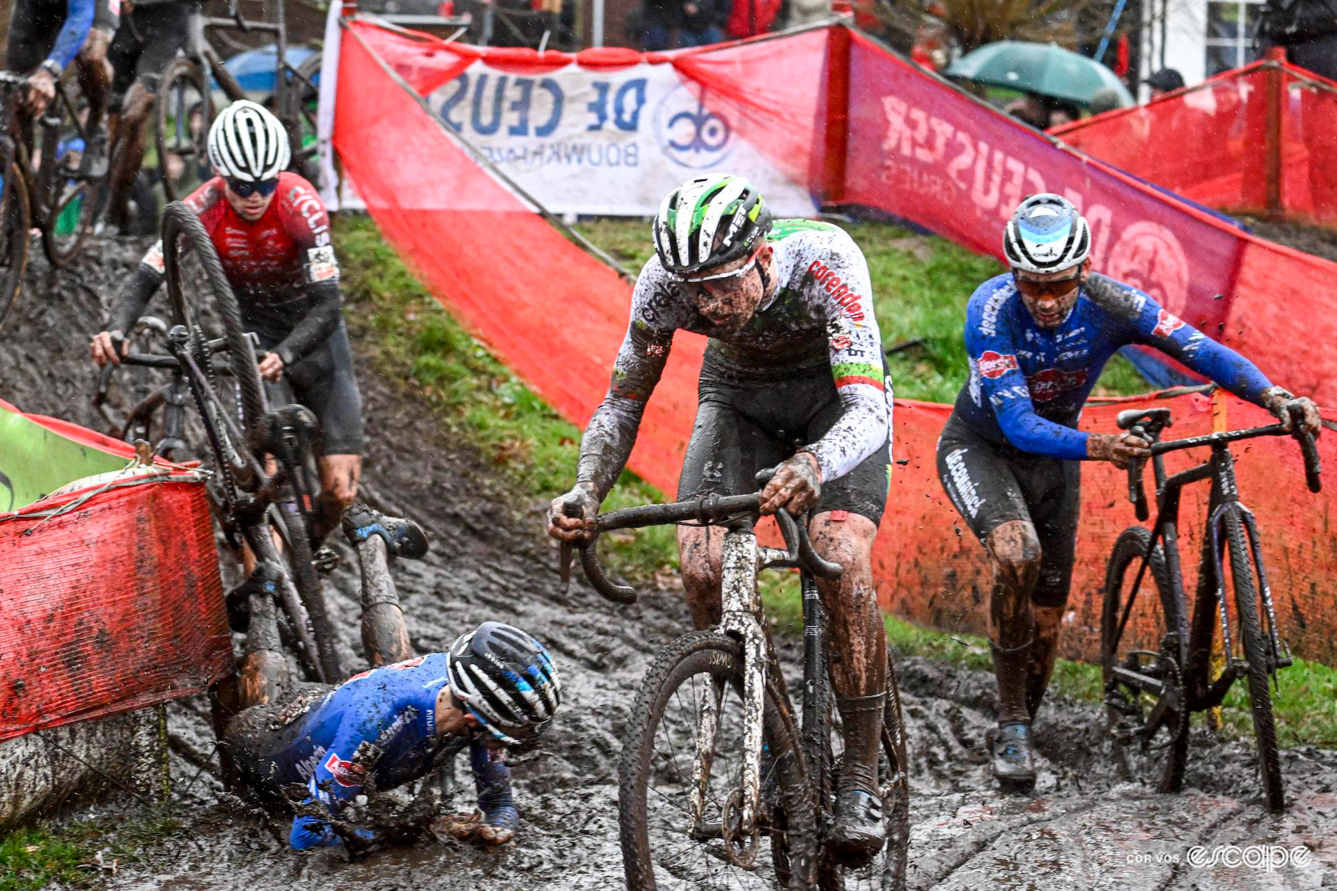 Riders work their way around a muddy corner as Jente Michels crashes into the sticky mud during Exact Cross Loenhout Azencross.