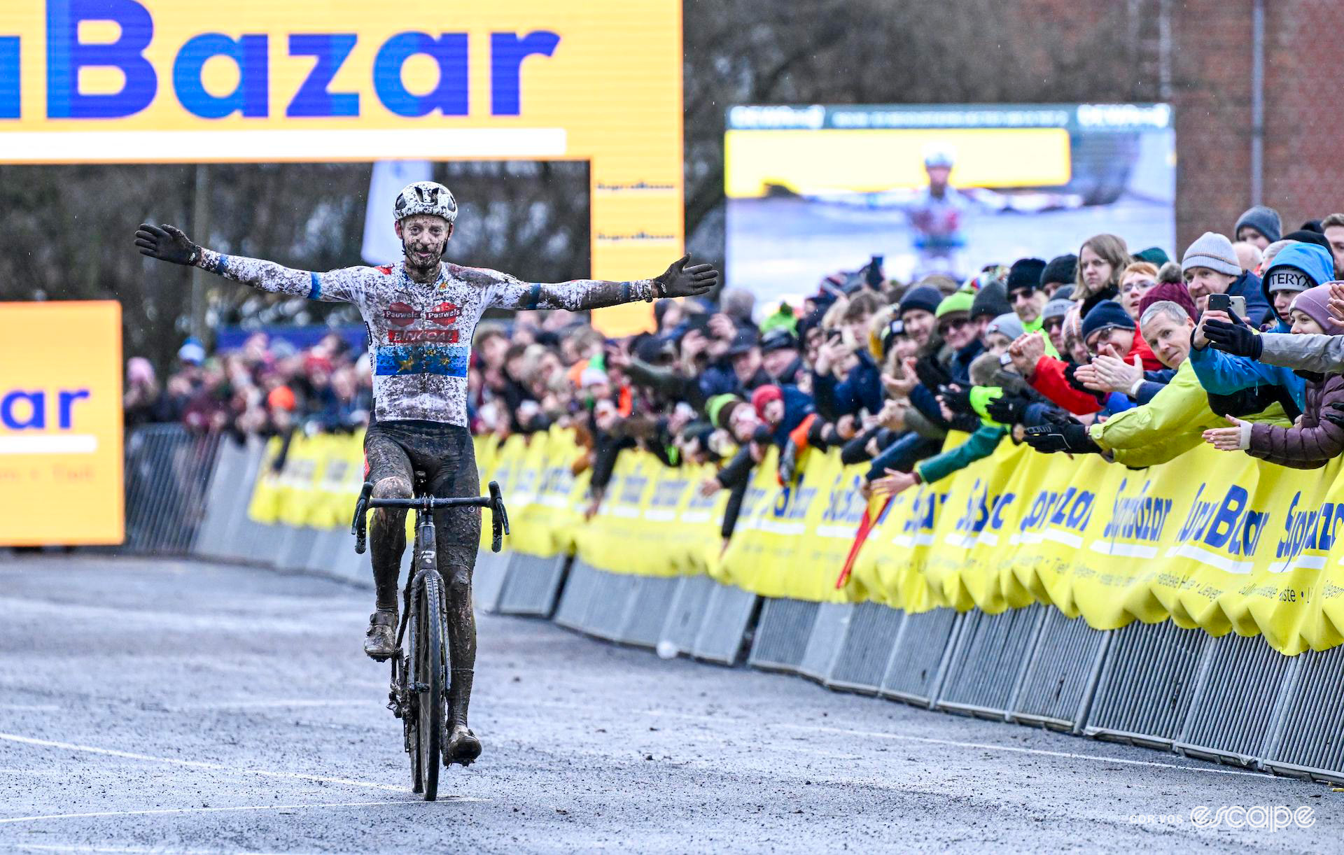 European champion Michael Vanthourenhout celebrates winning Hexia Cyclocross Gullegem, covered in splashes of mud.