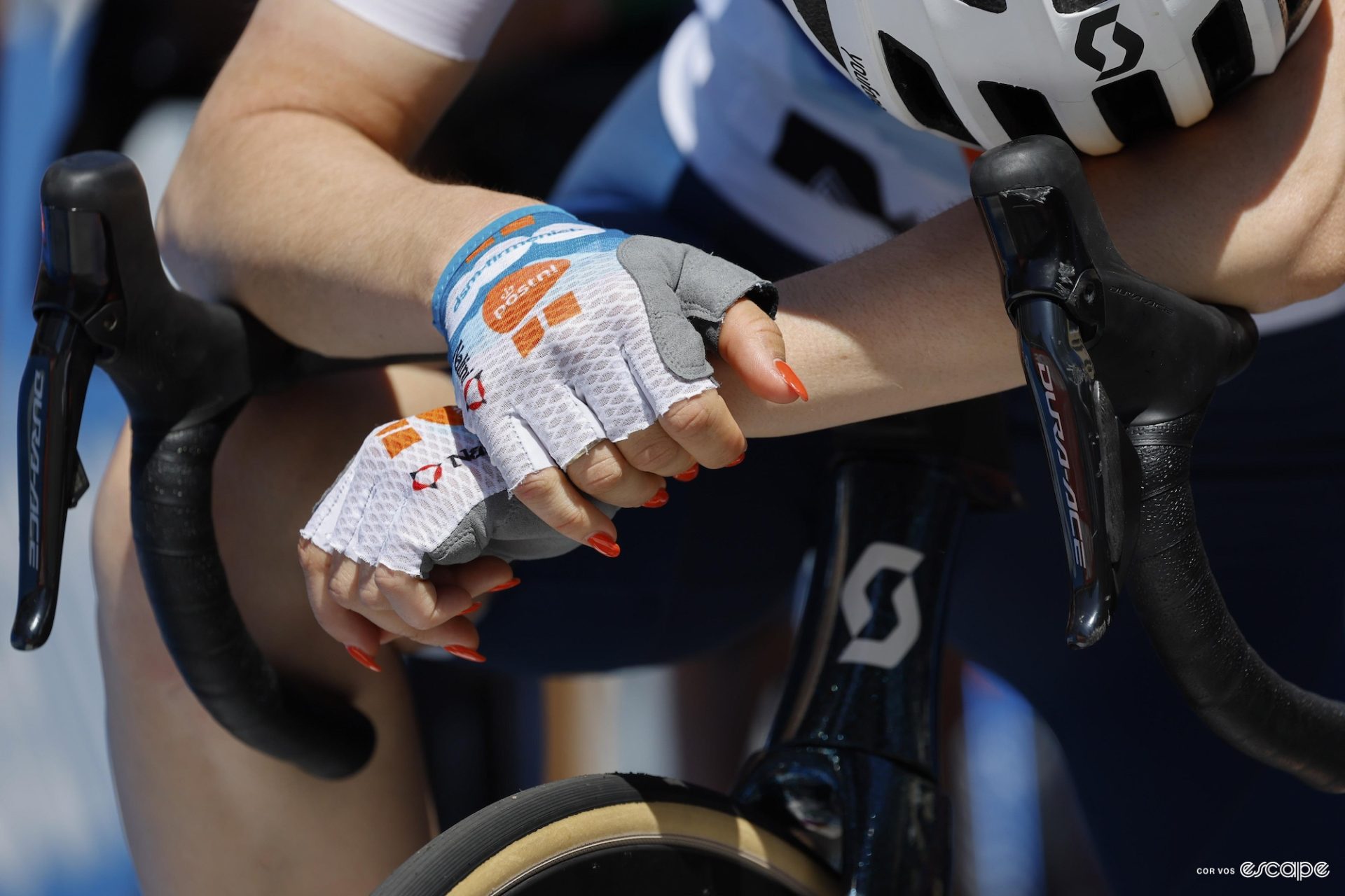 Francesca Barale bends over her handlebars after the third stage of the Tour Down Under with orange nails, the same color as the leader's jersey of the race.