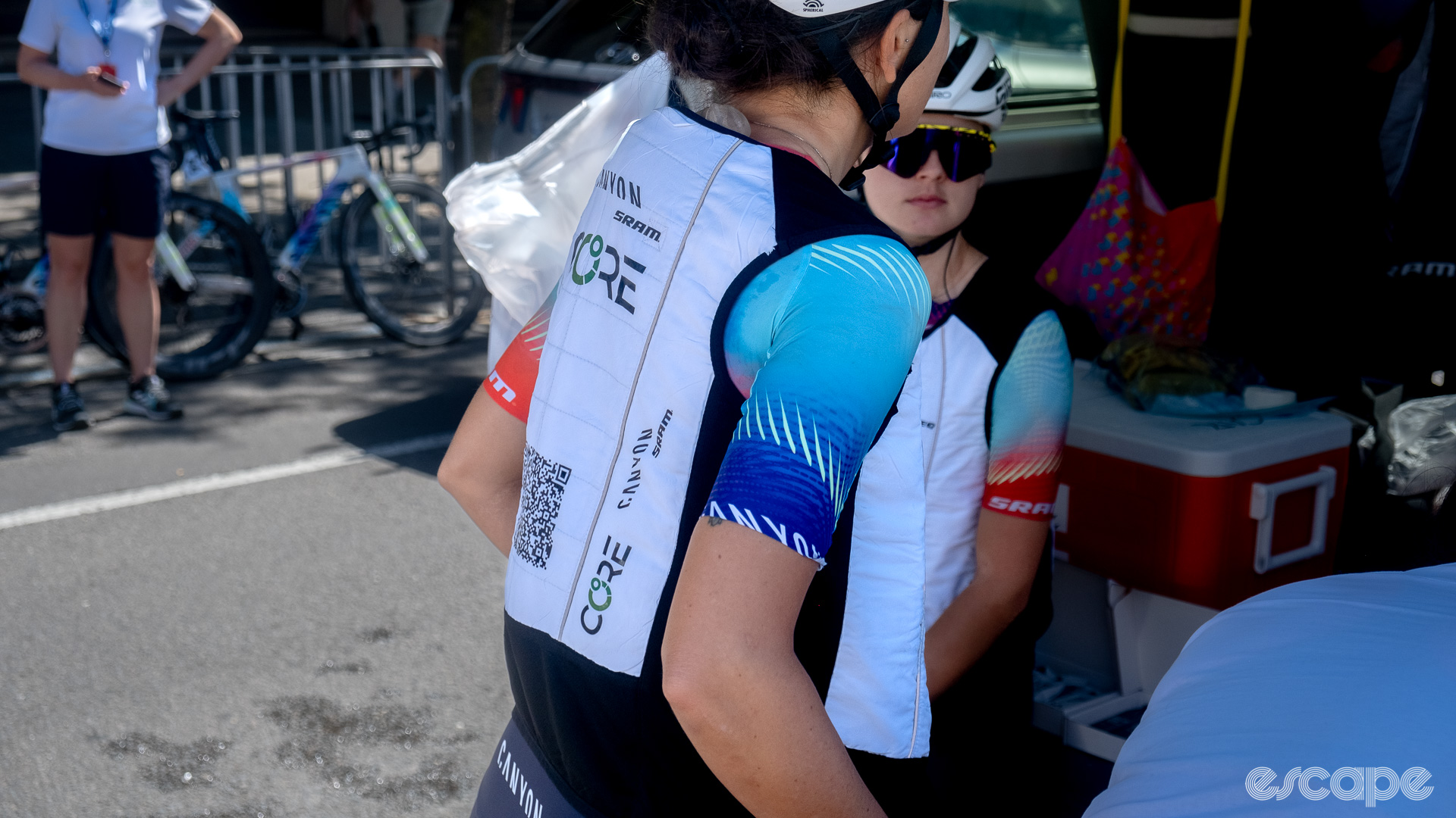 The photo shows two Canyon-SRAM riders wearing white team branded ice vests. 