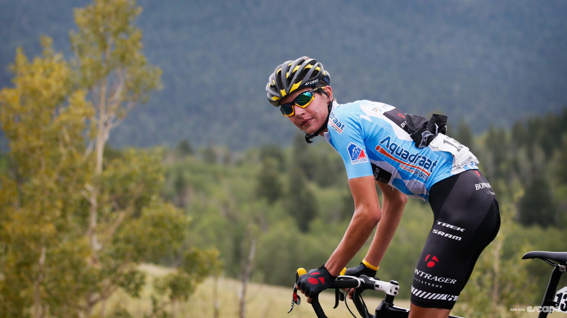 Joe Dombrowski looks at the camera while racing in the USA Pro Challenge. He's wearing the light blue jersey of the race's best young rider.