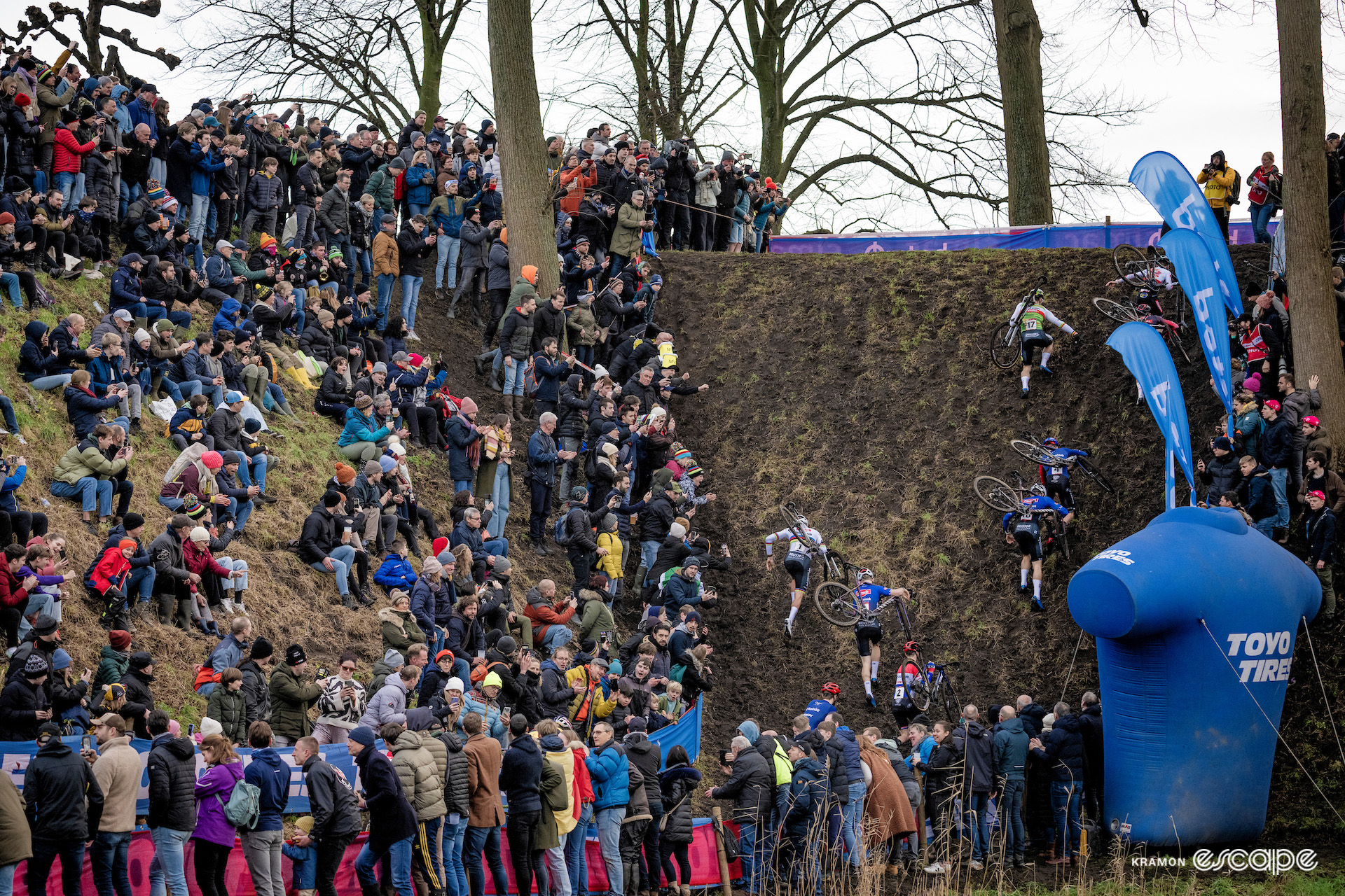 Wide view of the elite men taking on a steep climb during CX World Cup Hulst, watched by thick crowds.