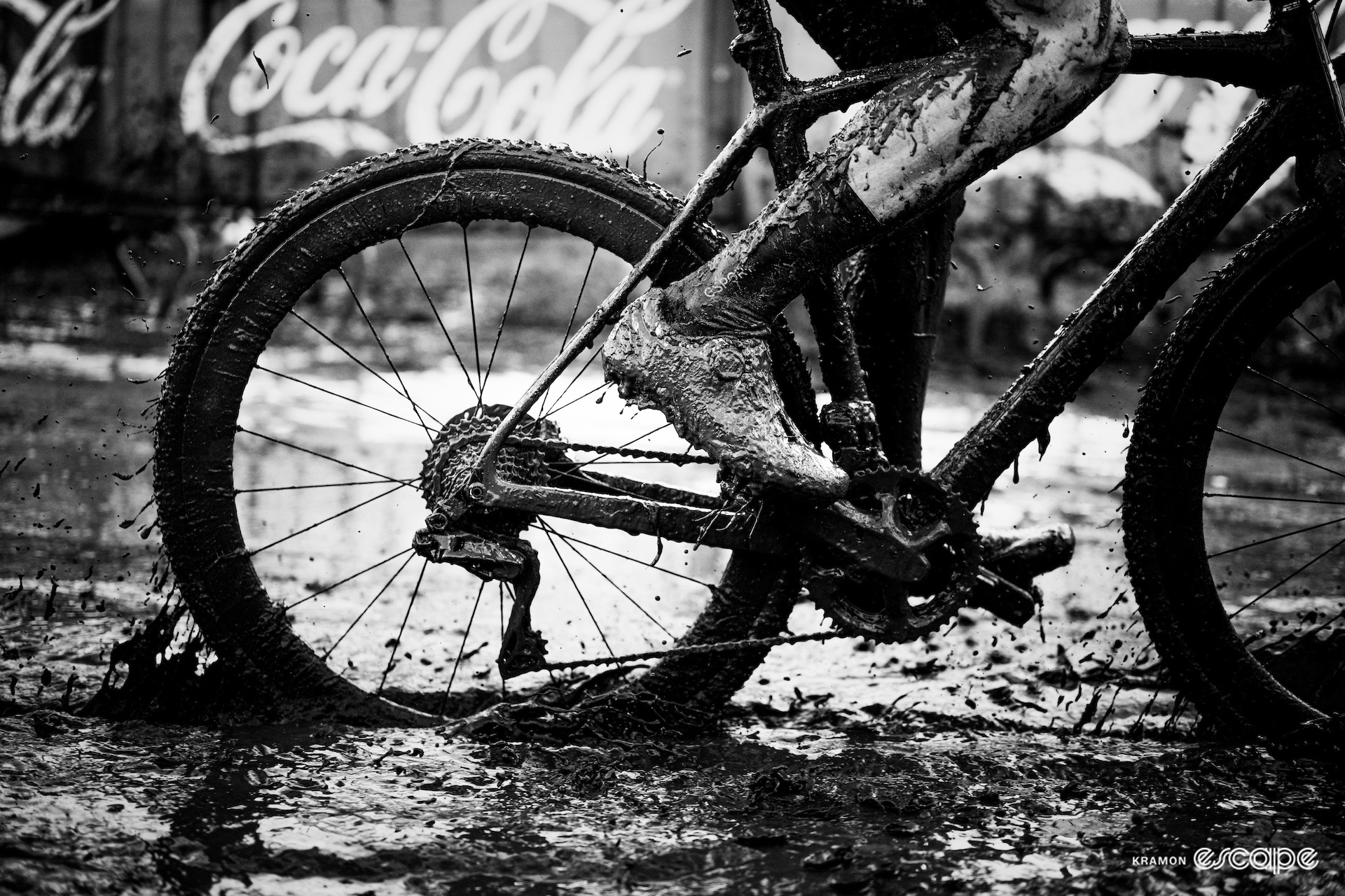 A black and white close-up of Felipe Orts's mud-covered bike and the rider's lower legs during the GP Sven Nys, X2O Trofee Baal.