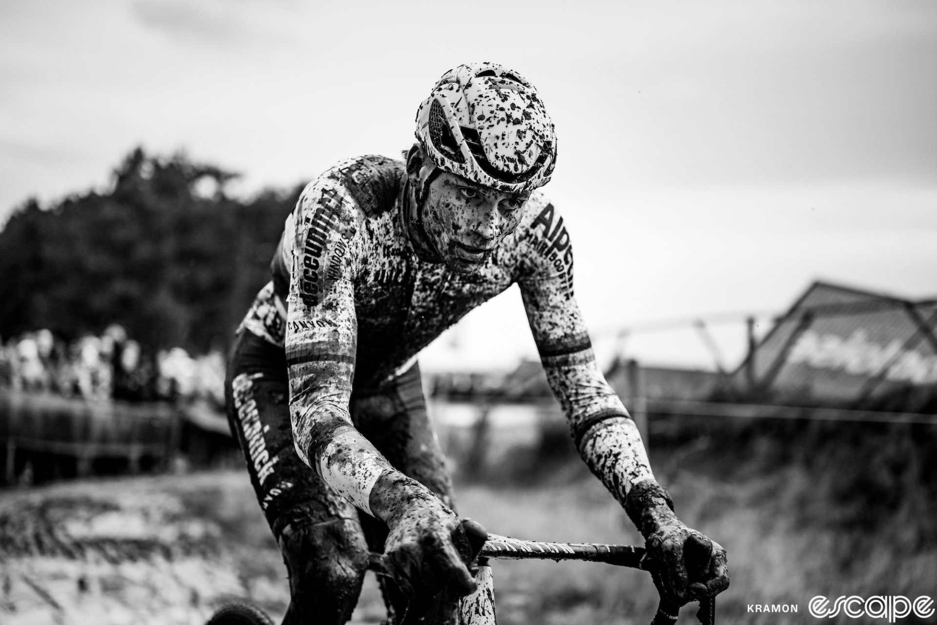 Mathieu van der Poel rides to a solo victory at the Grand Prix Sven Nys. The black and white image shows him close up, his World Champion kit covered in mud, with an intense focus on his face.
