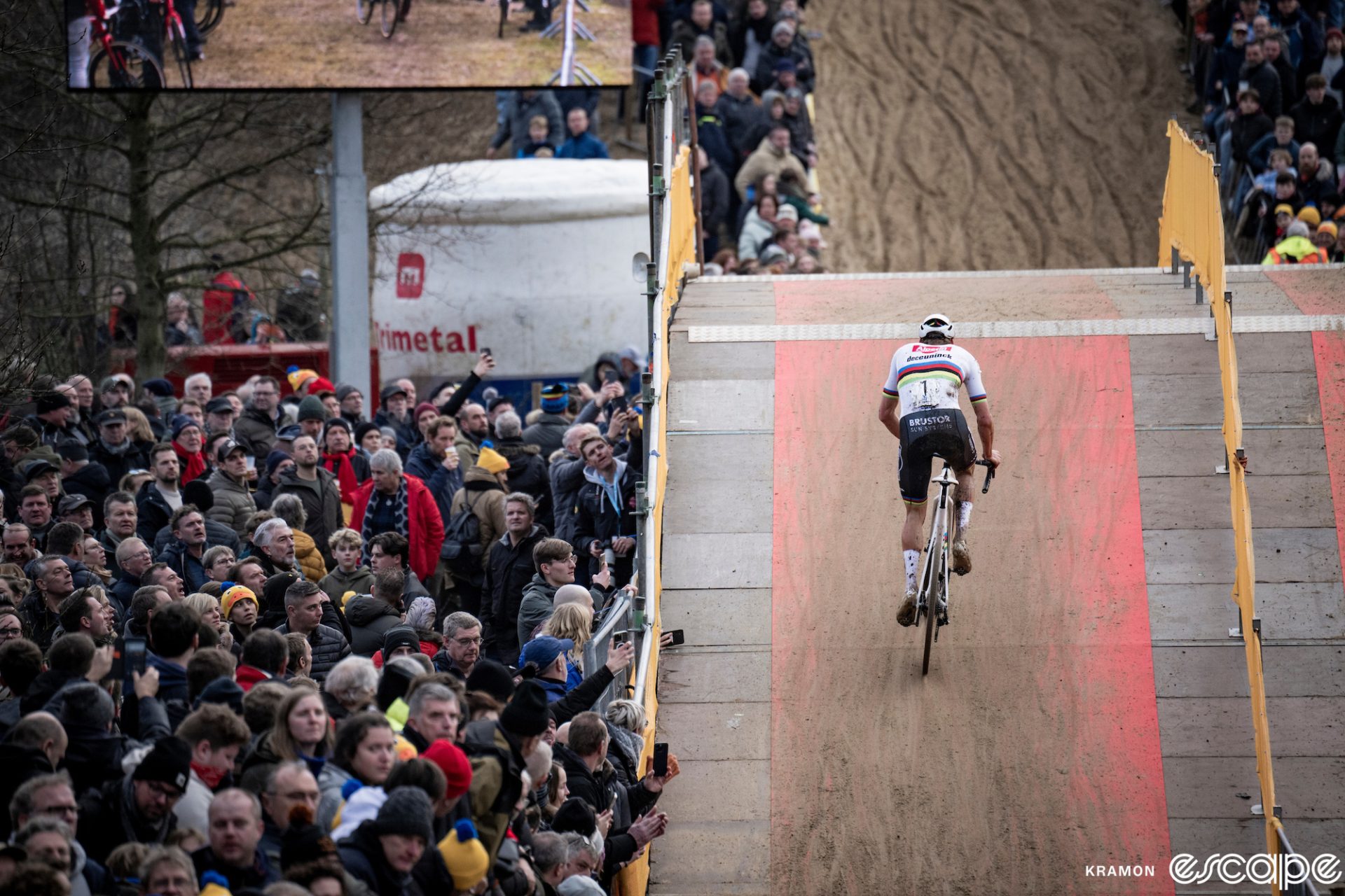 Mathieu van der Poel rides a flyover bridge at the X20 Koksijde cyclocross race. He's all alone, with crowds of fans watching him climb out of the saddle over the bridge.