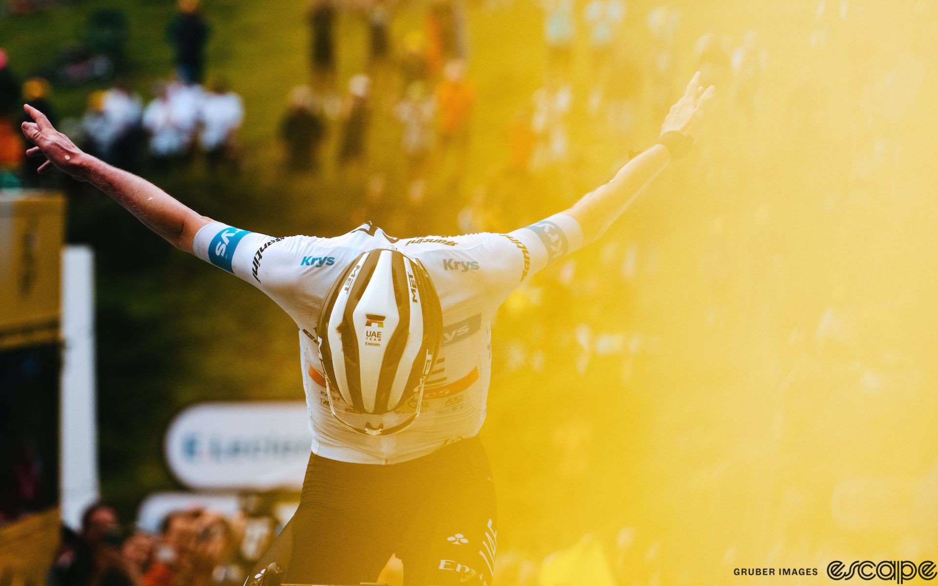 Tadej Pogačar takes a bow as he crosses the finish line to win stage 6 of the 2023 Tour de France. The image has a slight yellow flare on the right half, as if to foreshadow a yellow jersey.
