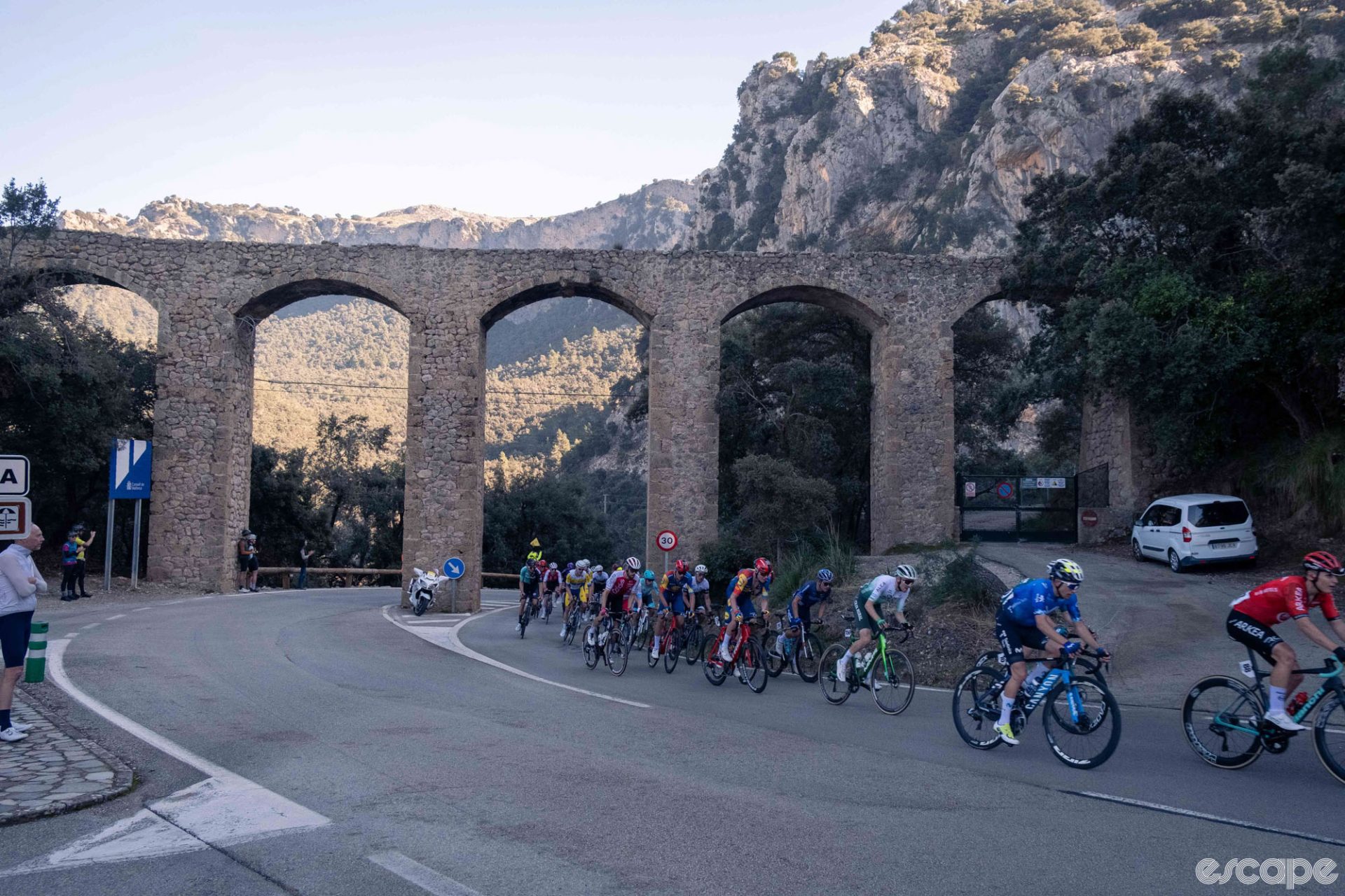The pack races under a stone aquaduct on Mallorca.