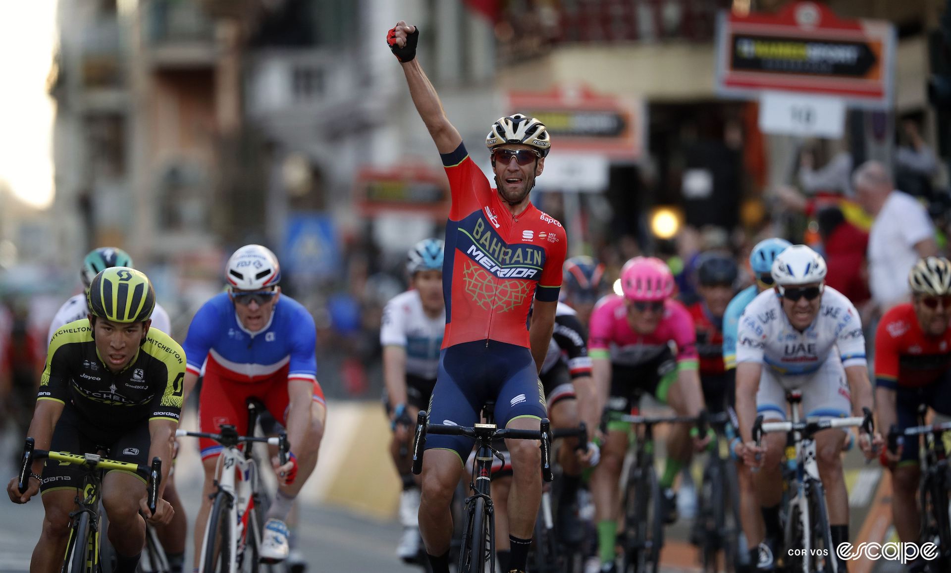 Vincenzo Nibali celebrates winning Milan-San Remo while a dejected Caleb Ewan leads the bunch across the line in second.