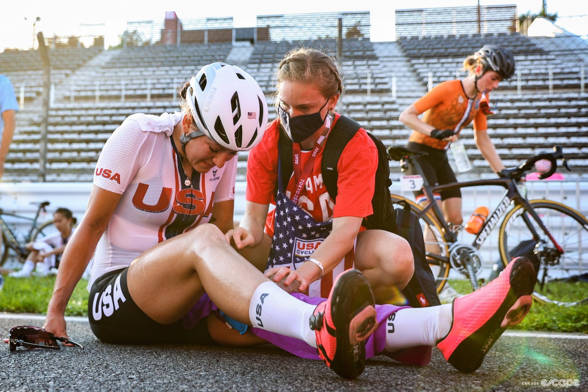 A staff member kneels down to talk to Chloe Dygert after a bike race. 