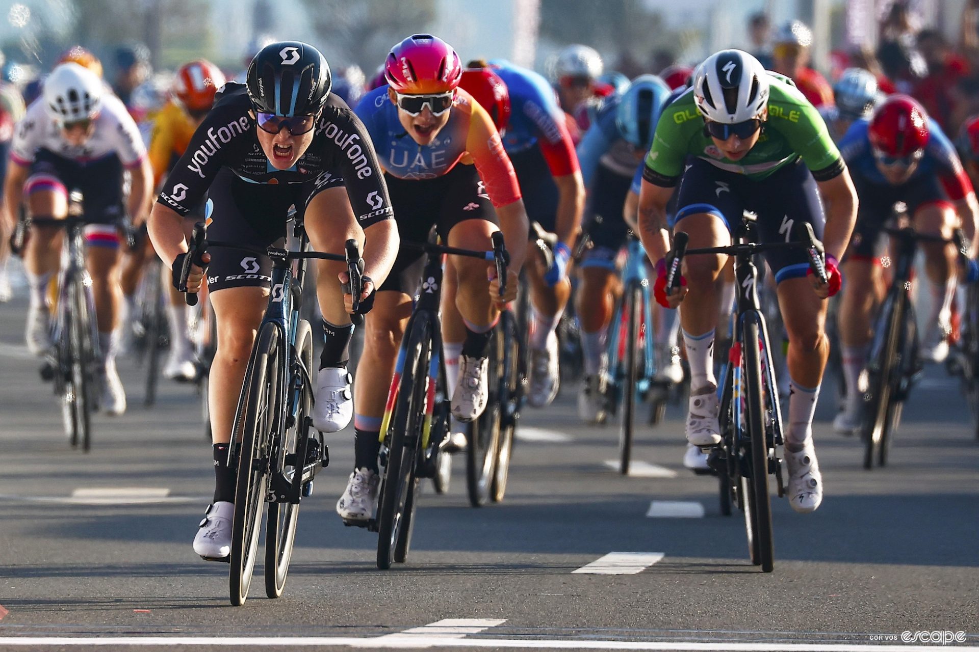 Charlotte Kool sprints it out at the UAE Tour. She's at the front, at least a bike length ahead of the chasing riders behind. Chiara Consonni is just off her wheel while Lorena Wiebes, in the green jersey for best sprinter, is to the right of Consonni trying to come around Kool.