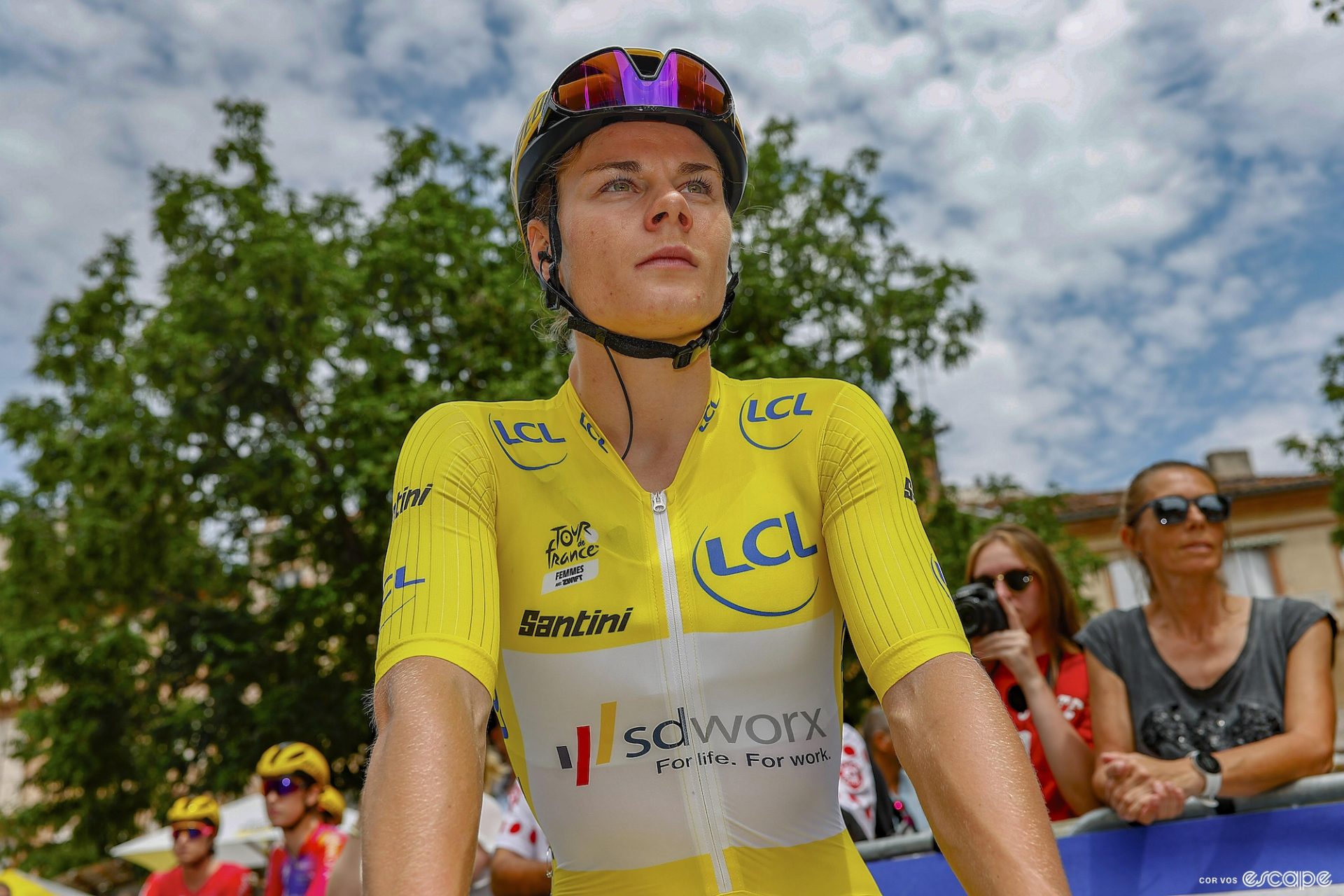 Looking up at Kopecky, wearing the yellow jersey, from the start line of a stage of the Tour de France. 