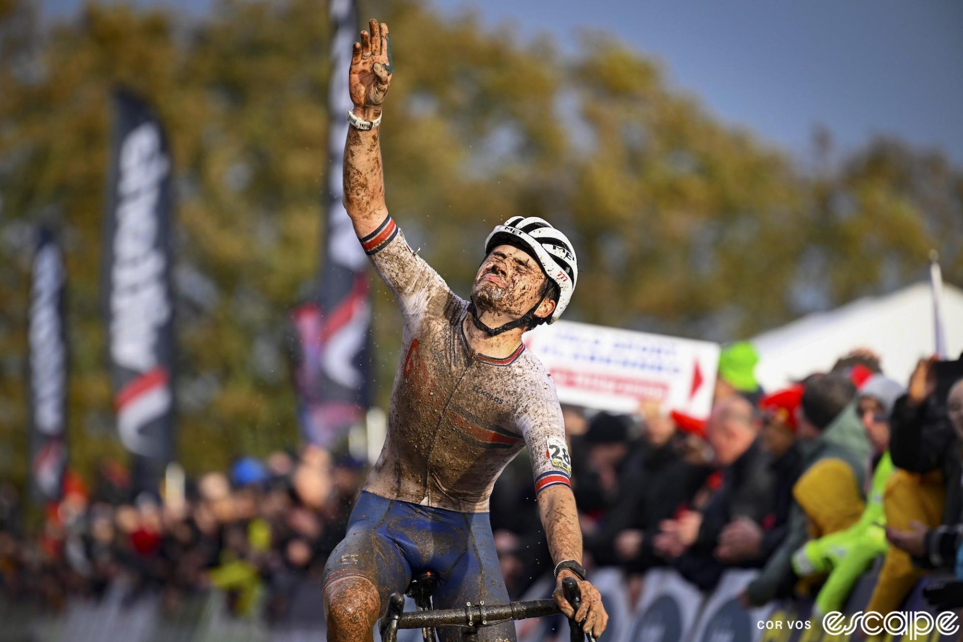 Cameron Mason gestures skyward as he crosses the finish line at the European Continental Championships in 2023. He is covered in mud but his face displays intense emotions as he closes his eyes and looks almost ready to burst into tears.
