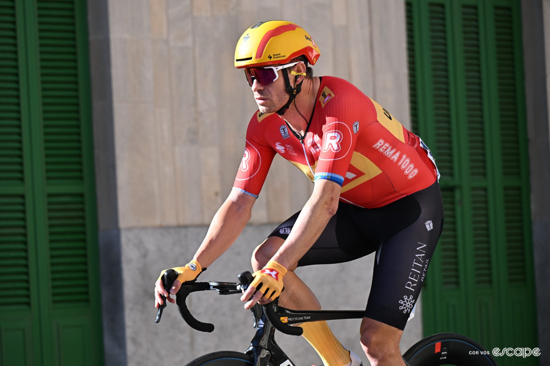 Alexandre Kristoff rides in a spring race in Mallorca. He's all alone in the shot, and has a serious expression on his face as if he's not having much fun.