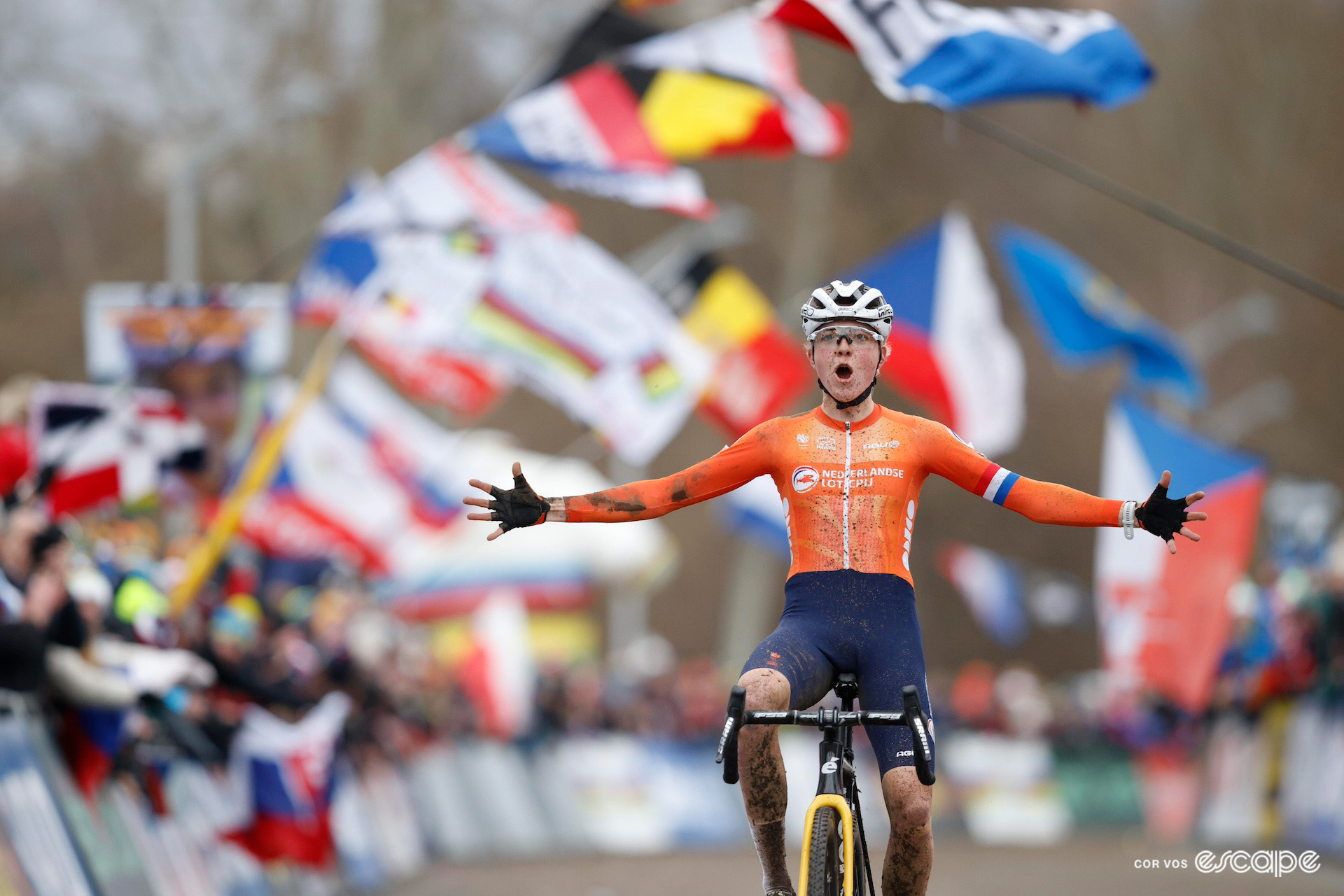 Dutch rider Fem van Empel celebrates winning the 2024 Cyclo-Cross World Championships in Tábor against a backdrop of flag-waving crowds.