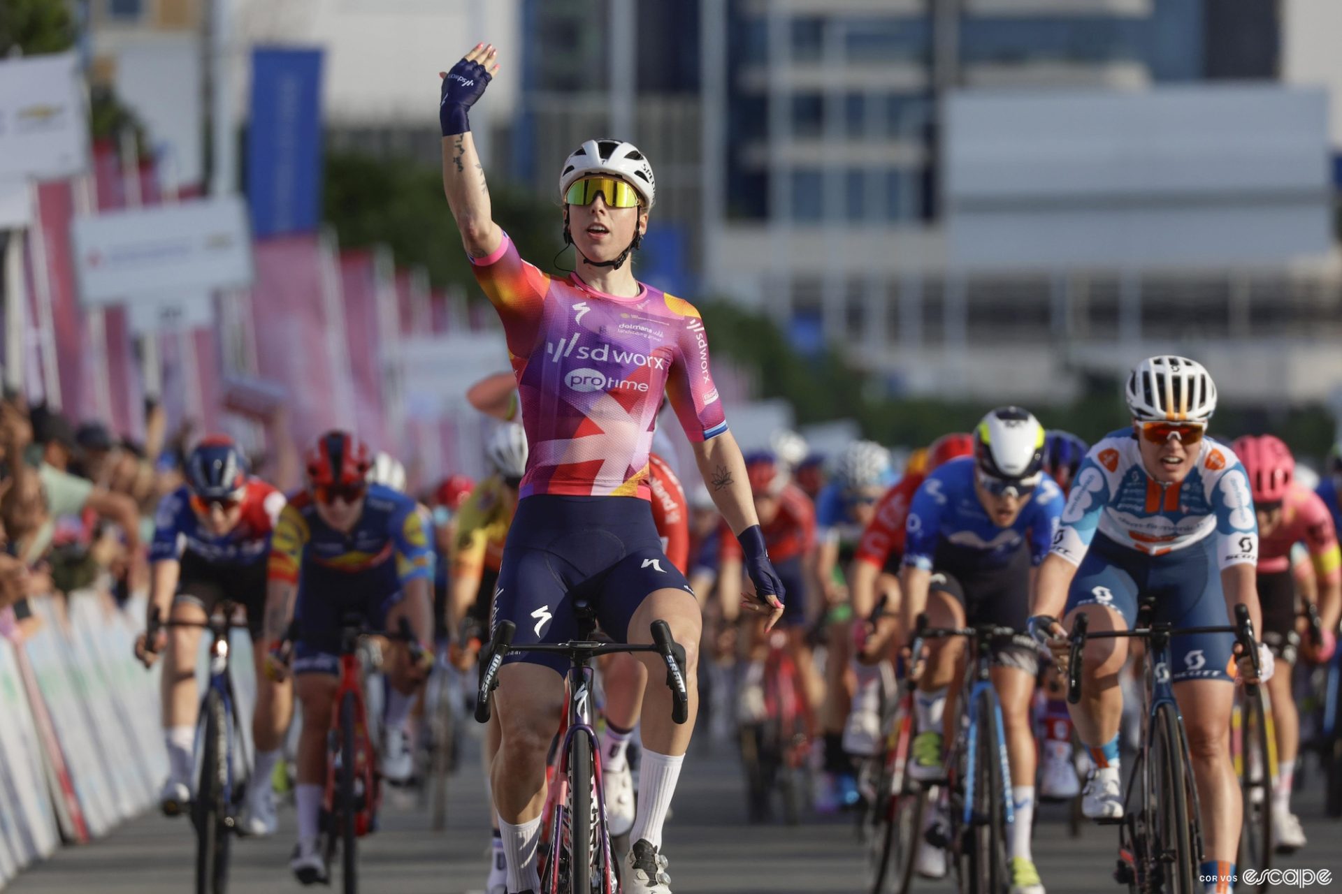 Lorena Wiebes raises her hand in victory at the finish of a bike race.