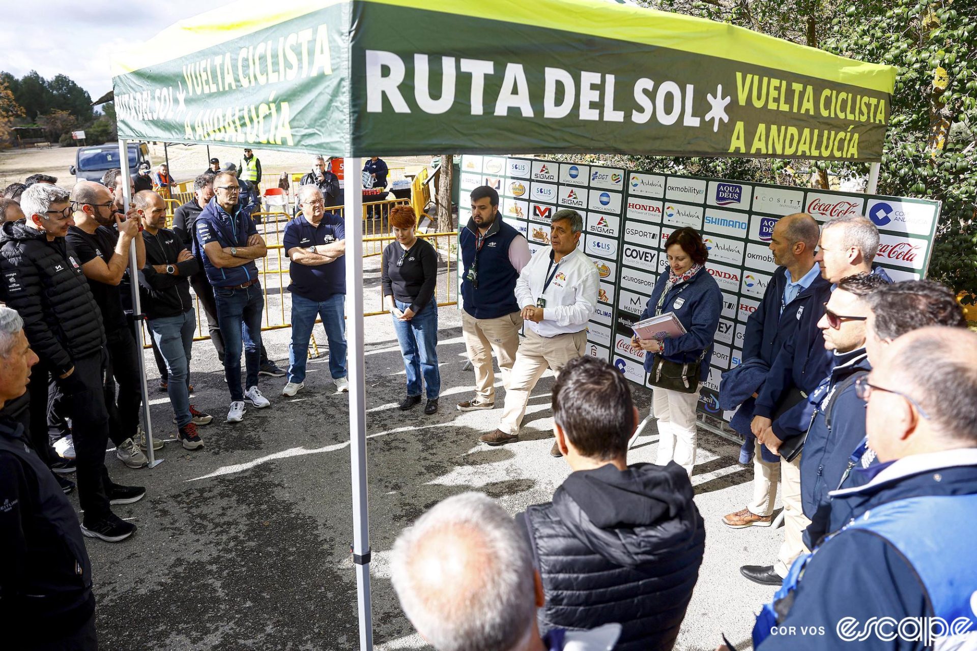 Race organizers of the Ruta del Sol hold an impromptu staff meeting to discuss the radical shortening of the race. They're standing in a circle under a RdS pop-up tent as director Joaquin Cuevas announces changes.