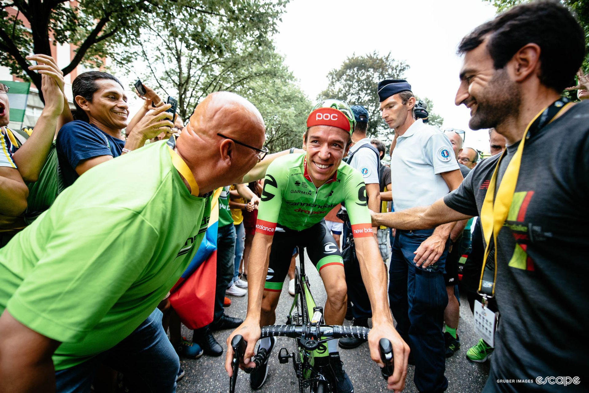 Uran, smiling, is surrounded by fans and team staff.