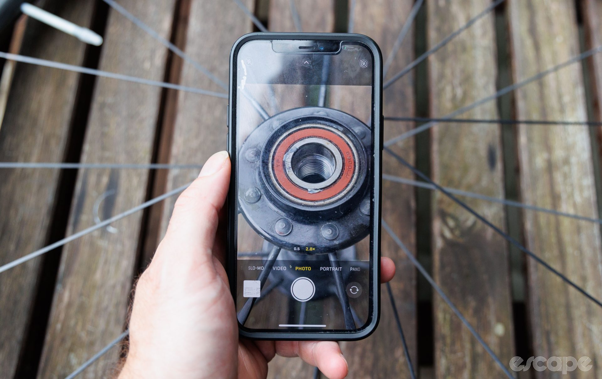 A smartphone taking a picture of an installed bicycle hub bearing that is otherwise hard to read. 