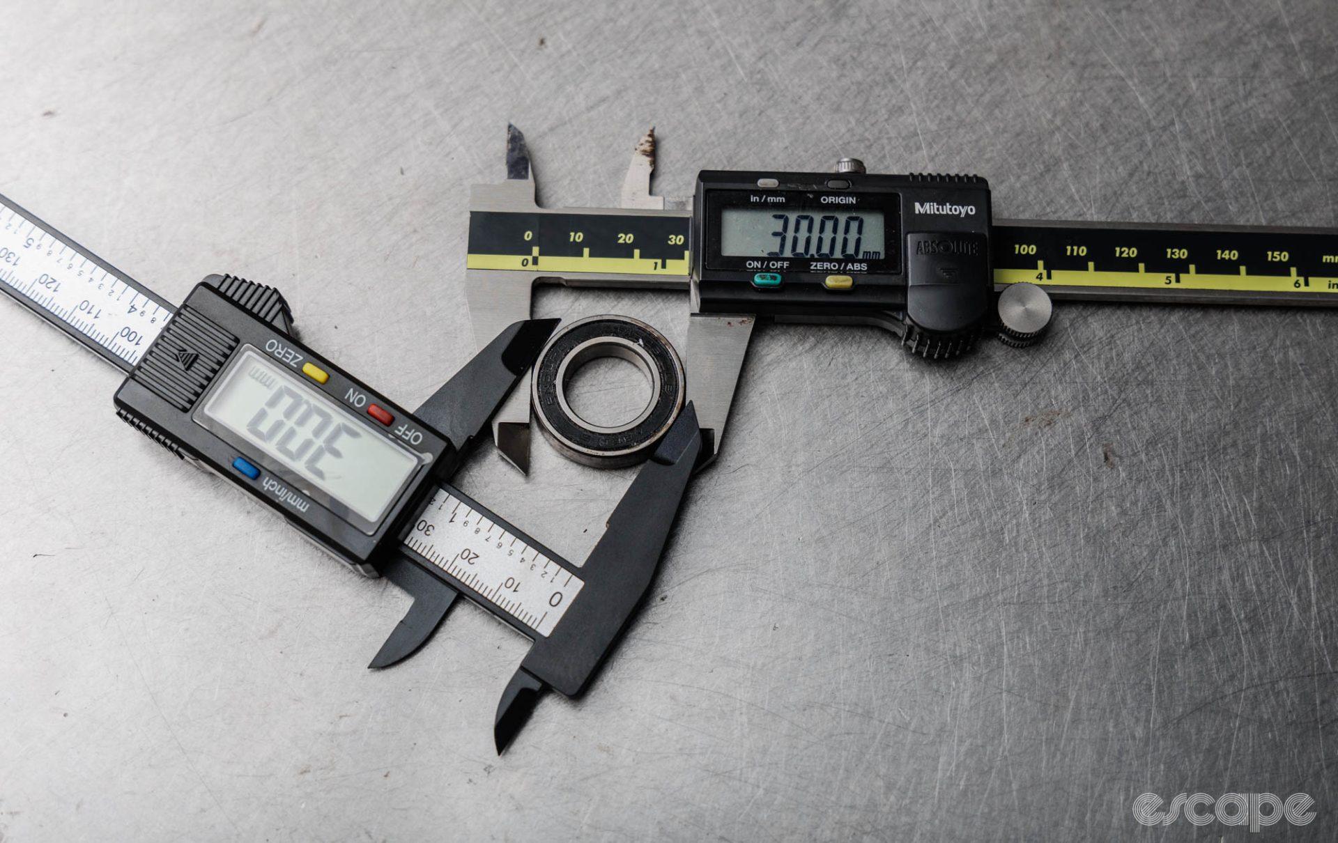 High-end digital calipers and an ultimately cheap plastic digital caliper measuring the same bearing. Both read 30 mm. 