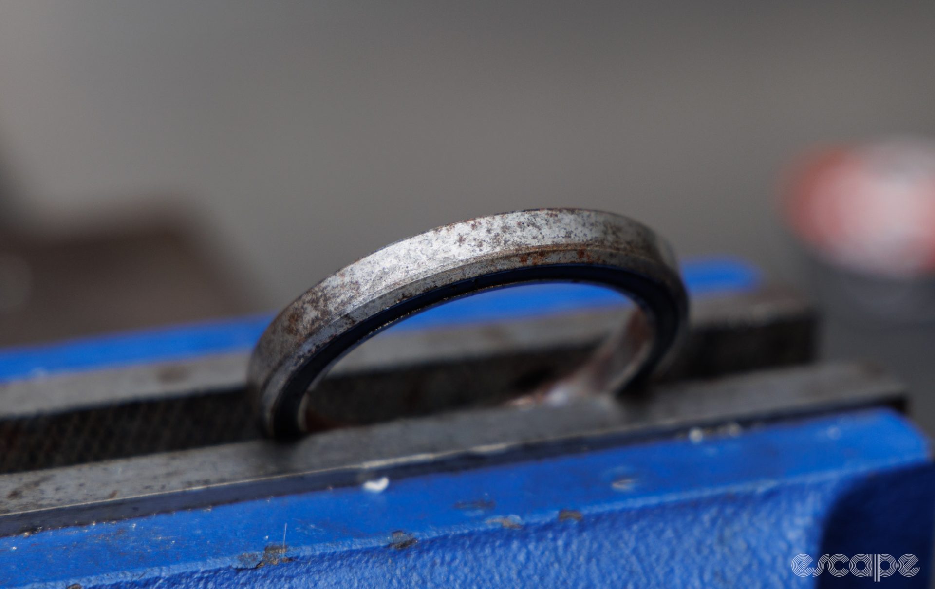A rusty headset bearing sits on top of a bench vise. 