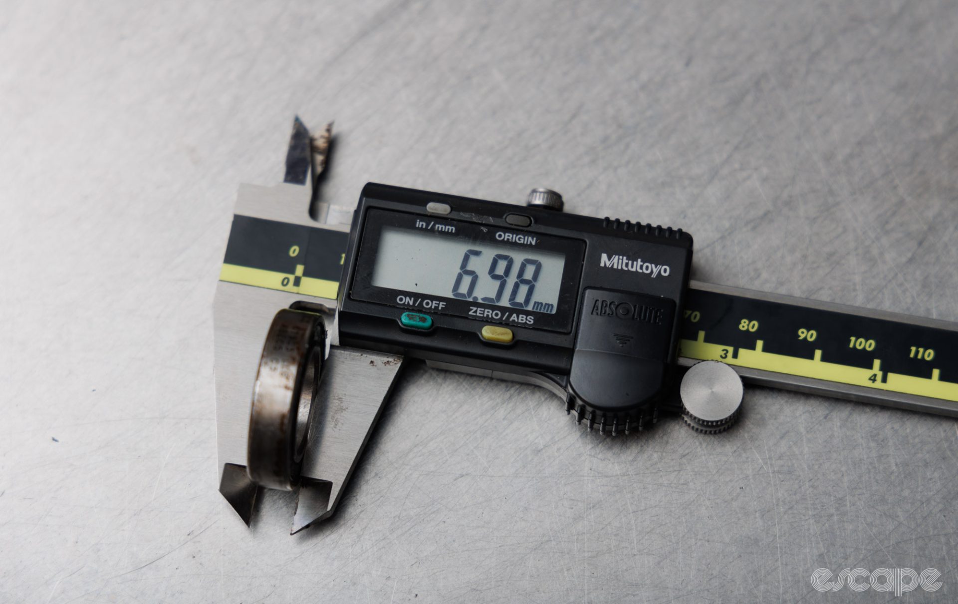 The height of a cartridge bearing is measured with digital calipers. The calipers read 6.98 mm. 