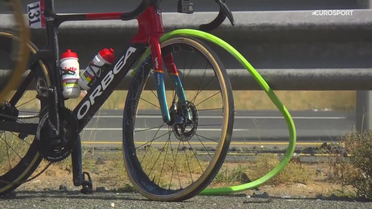 Thomas De Gendt's bike sits against a railing at the UAE TOur. The front wheel has blown off the rim and the internal foam tire liner has come completely out, and looks like a very thin, lime green pool noodle.