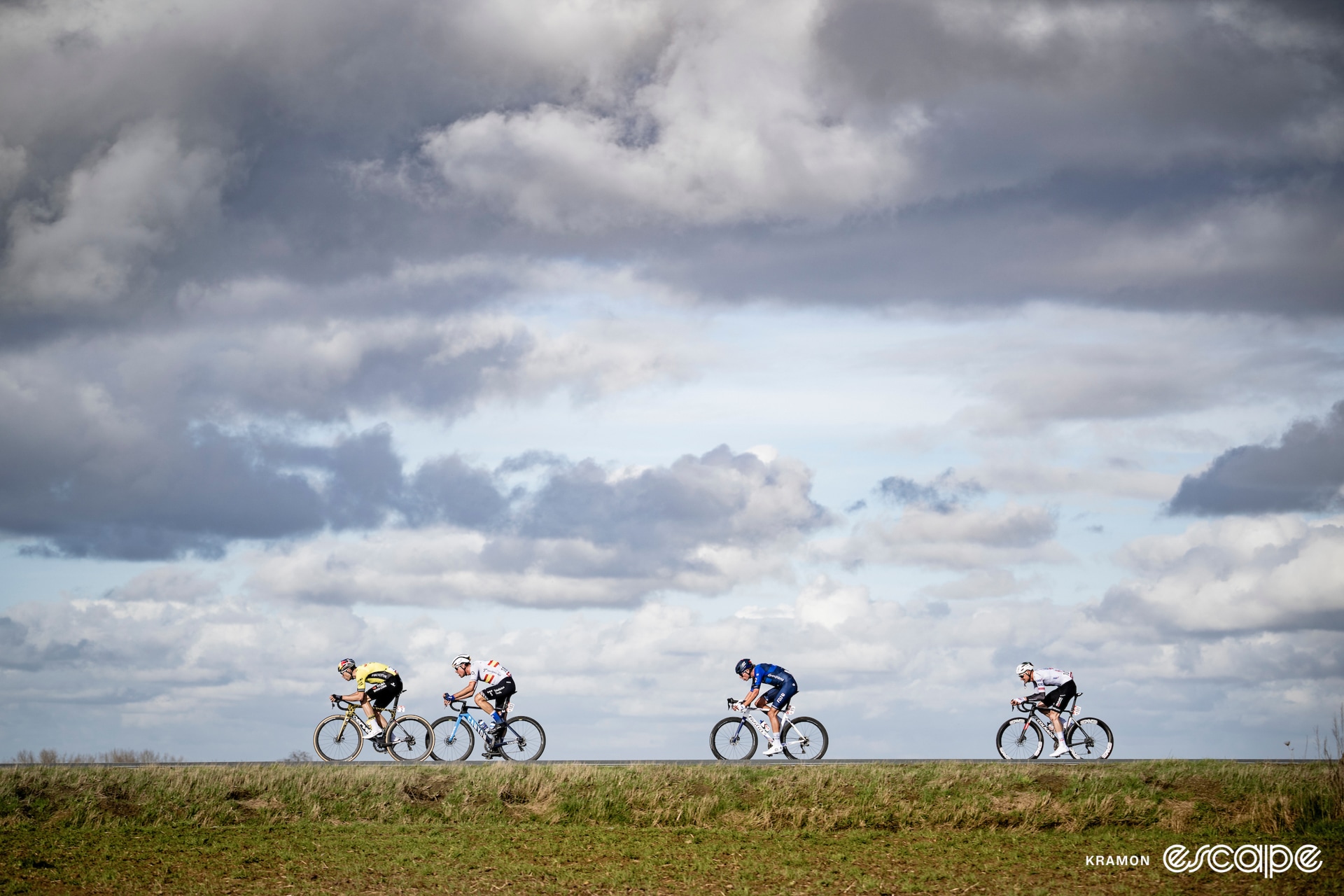 The four lead riders in front of a moody sky