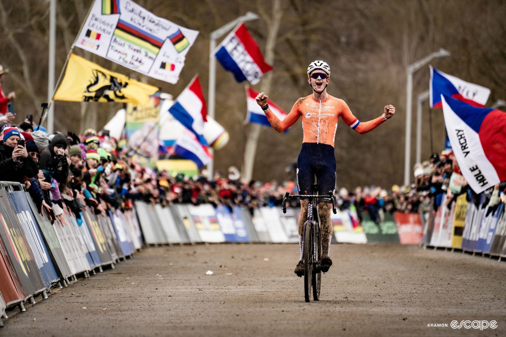 Dutch under-23 rider Tibor del Grosso celebrates winning the 2024 Cyclo-Cross World Championships in Tábor, a Dutch flag waving in the crowd behind him.