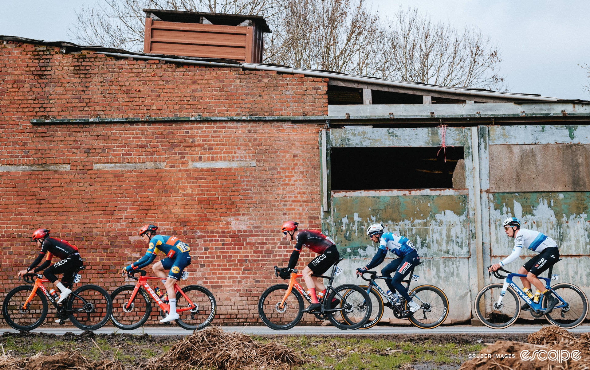 A handful of riders in front of a wall with interesting textures.