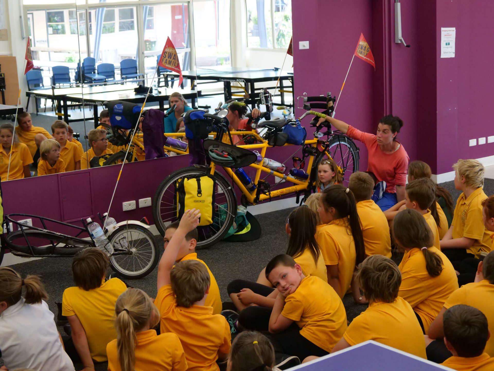 The Hughes family in front of a class full of kids with their bikes, Nicola talking to the students. 