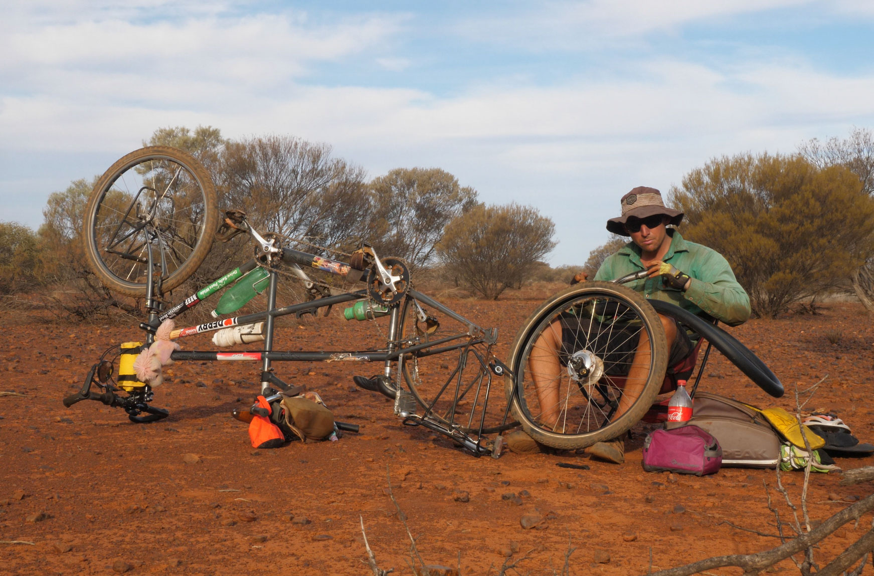 Andrew fixes a puncture on a dirt roadside. 