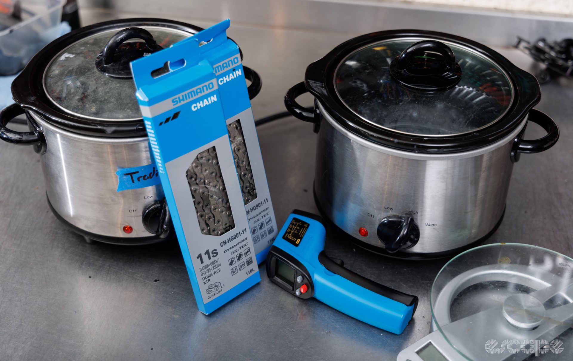 Two slow cookers on a bench, with new in packet Shimano chains and a digital thermometer. 