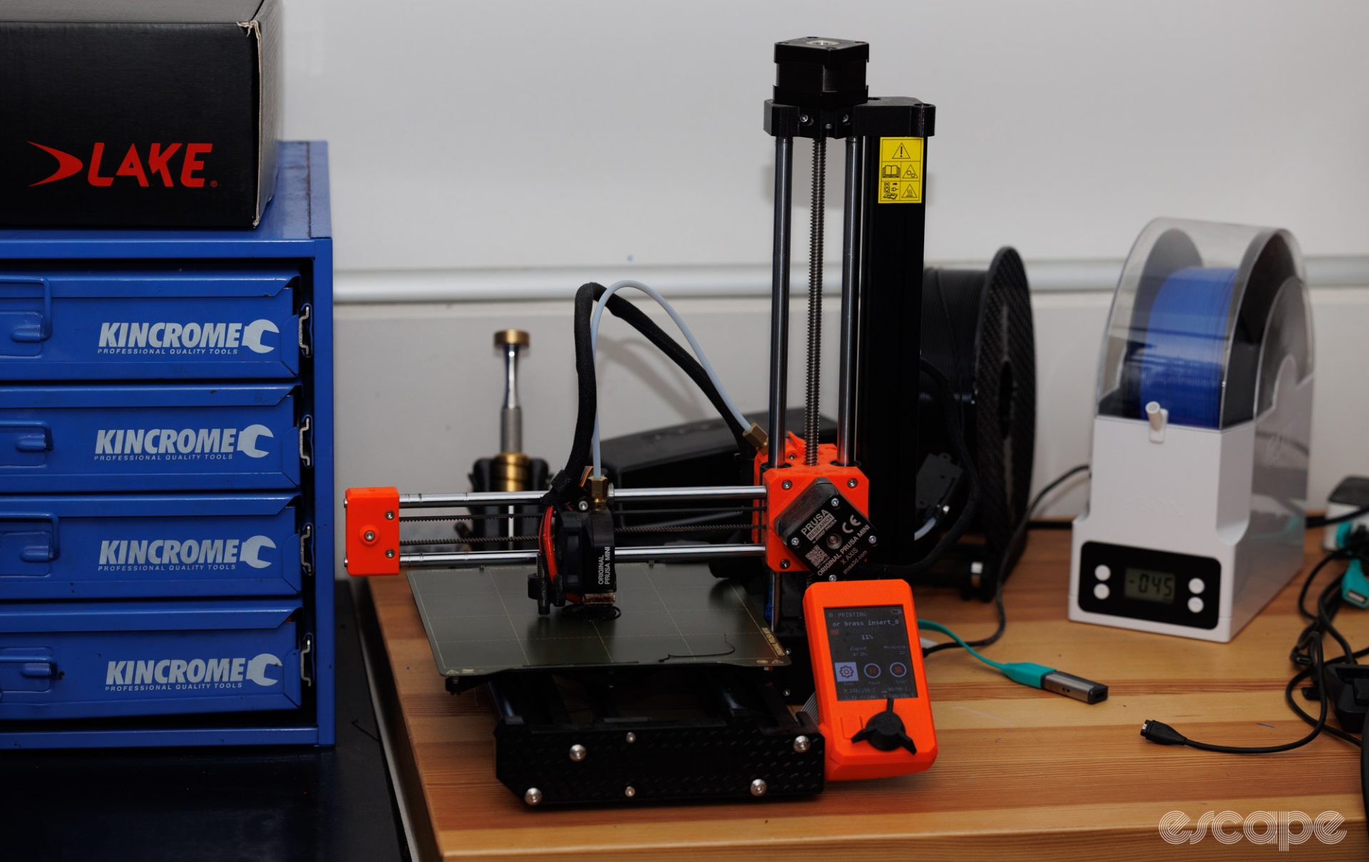 Prusa Mini+ 3D printer sitting on a desk in use. 