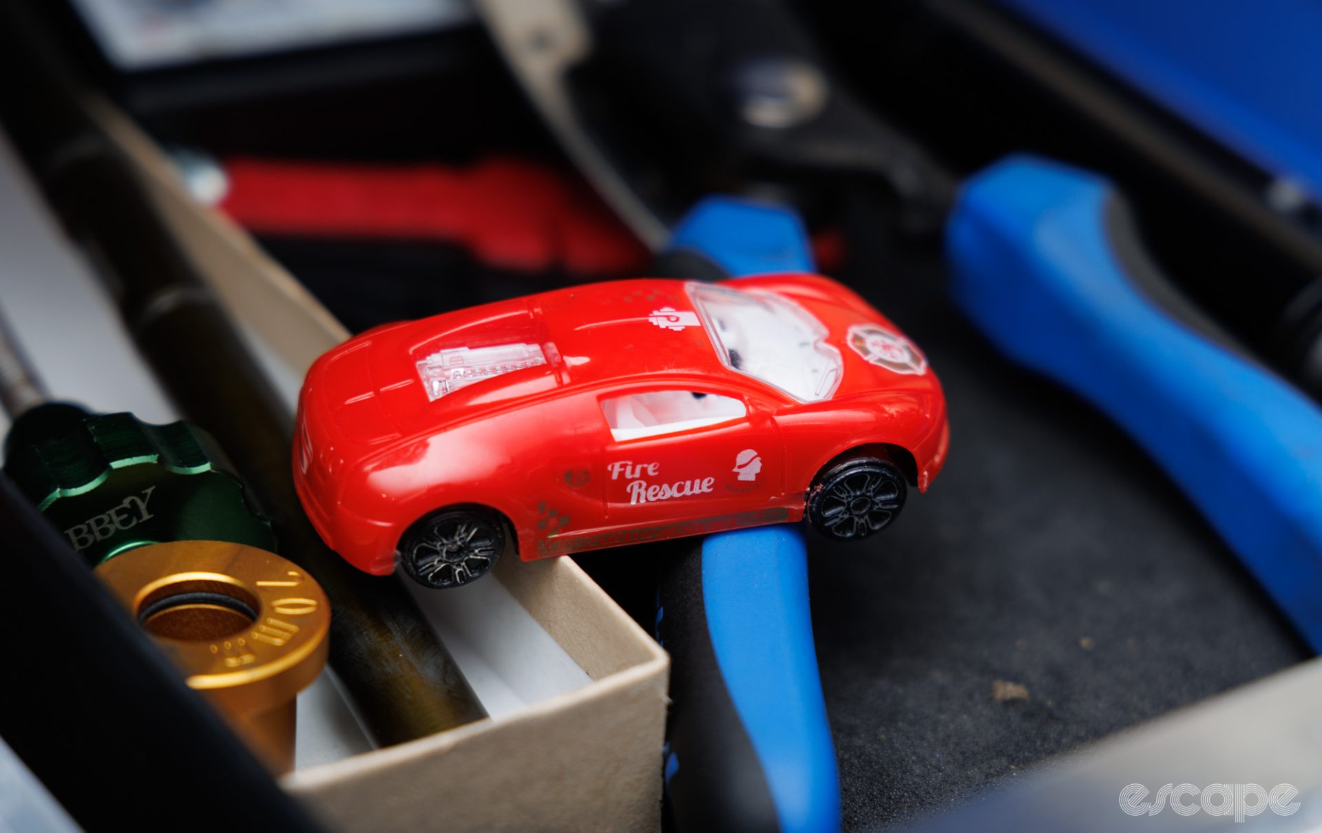 A toy car sits on a selection of a wheel-related tools. 