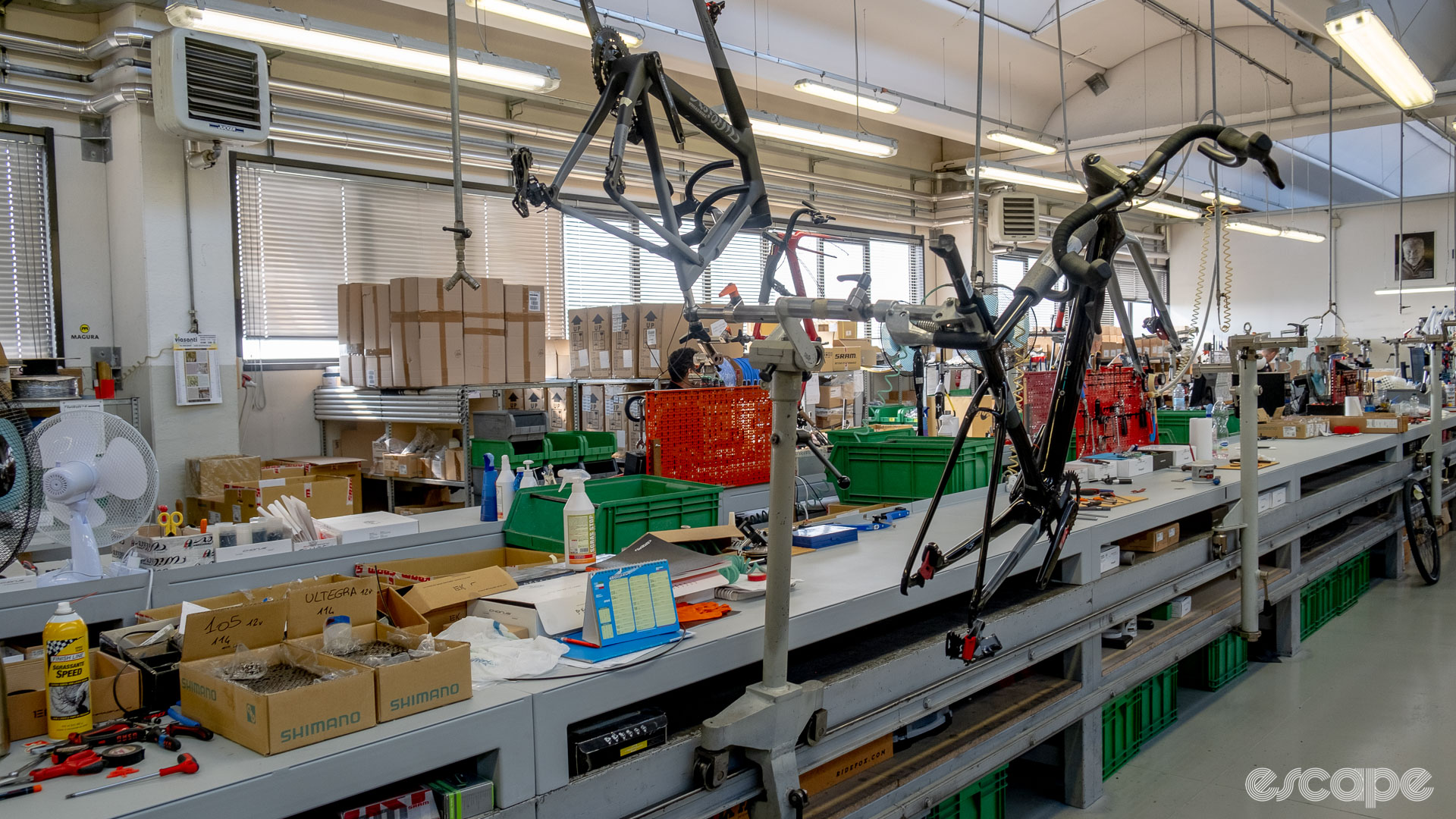The photo shows two bikes on bike stands on Wilier's assembly line. One bike is held upside down.