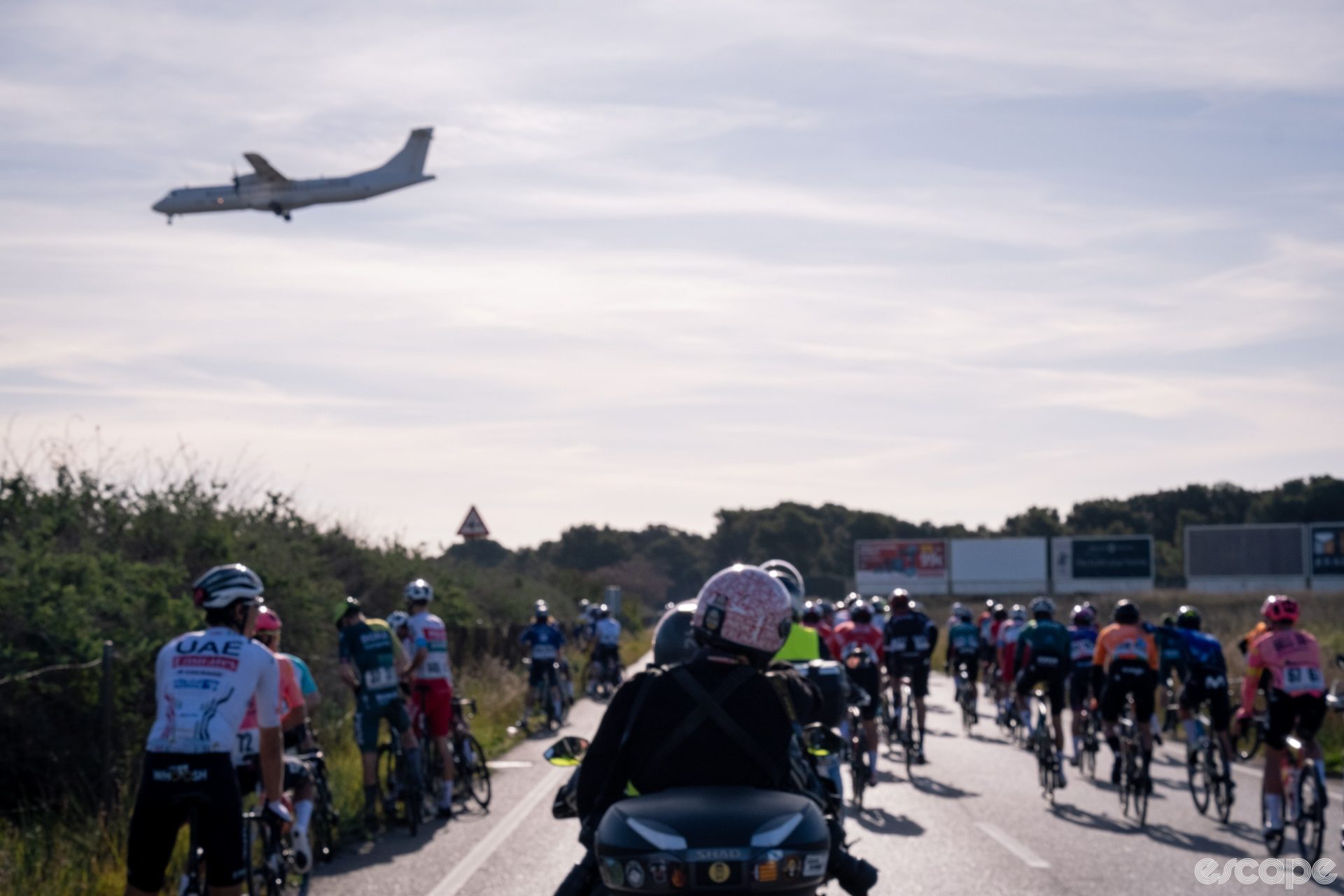 A plane passes over the peloton at Trofeo Palma 2024.