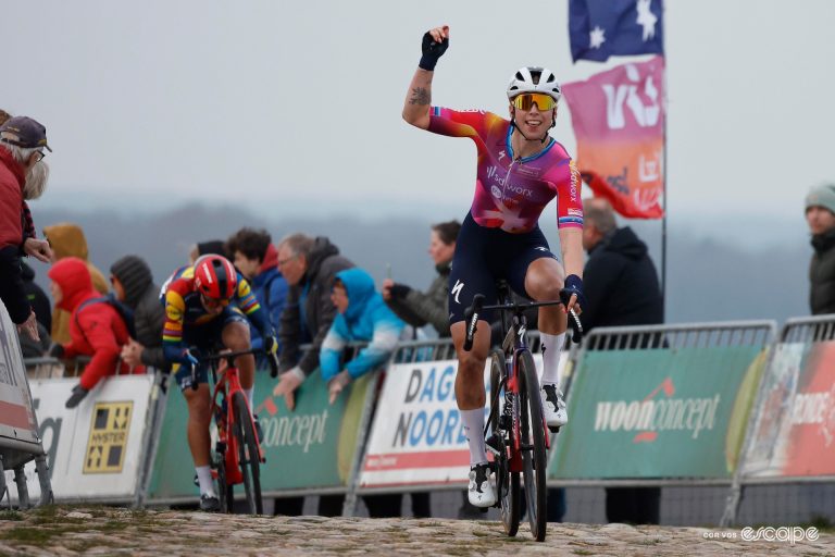 Lorena Wiebes raises one hand in celebration at the end of Ronde van Drenthe, runner-up Elisa Balsamo digging deep behind.