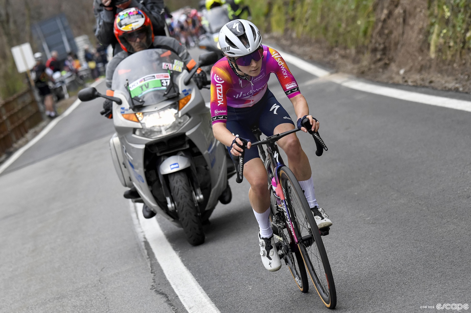 Niamh Fisher-Black rides in a solo breakaway at Trofeo Alfredo Binda. The pack is close behind, partly obscured by a TV moto righ ton her wheel.