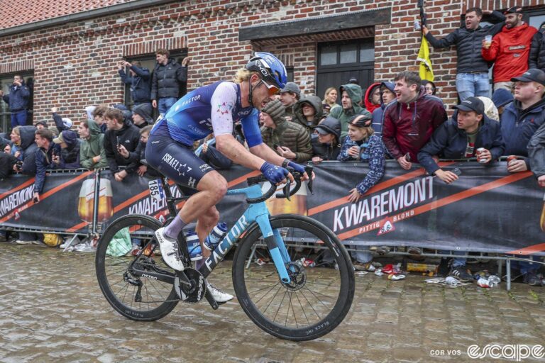 Riley Sheehan rides past a Kwaremont sign on a cobbled climb at the Tour of Flanders.