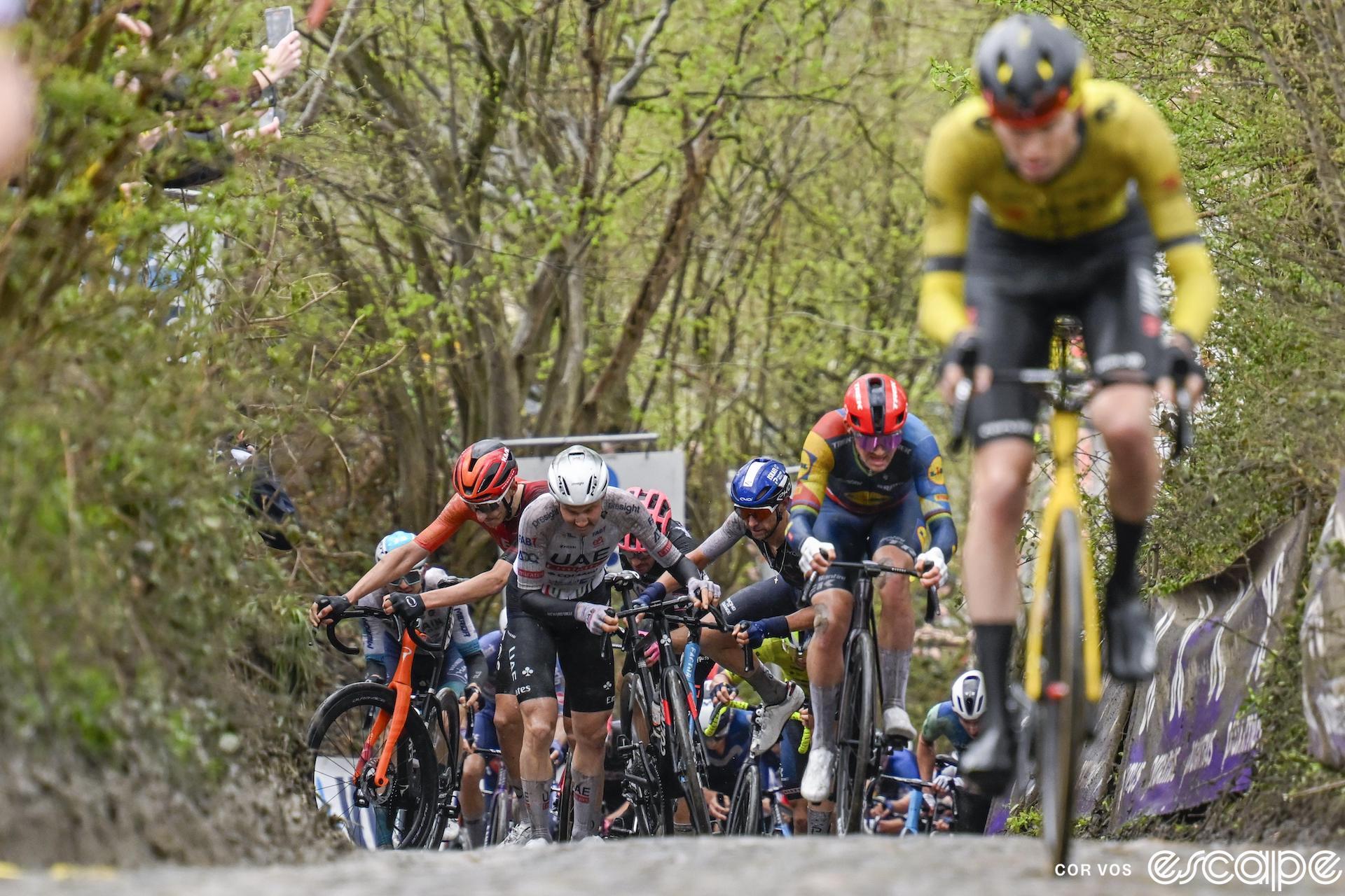 Left to right, Ben Turner, Tim Wellens, and Dylan Teuns unclip off their bikes on the steep, slippery Koppenberg just behind Mads Pedersen and Matteo Jorgenson.