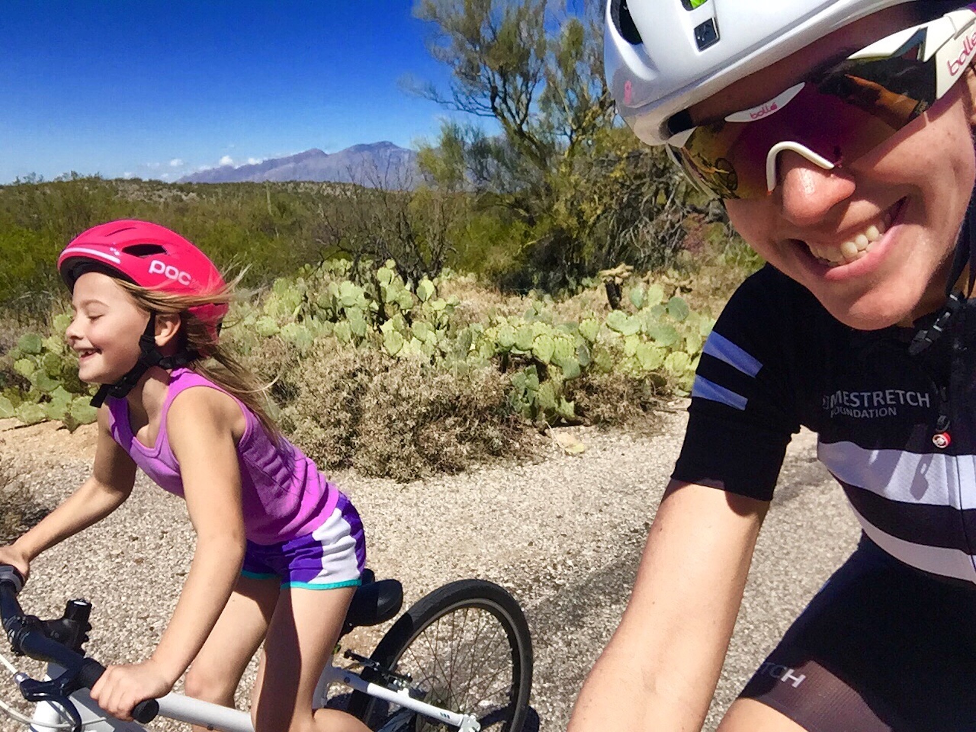 Kathryn Bertine takes a selfie out on a ride with a young girl, Ava, who she met while riding. Both have wide smiles, and Ava is obviously half-wheeling Kathryn.