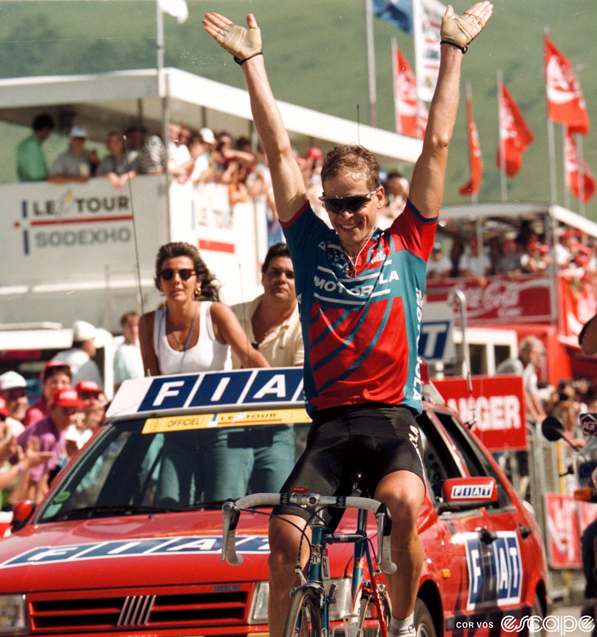 Hampsten throws his arms in the air as he crosses the finish line to win the Alpe d'Huez stage of the 1992 Tour de France. He's slightly balding now, the tousled head of curls thinning, and has a wide smile on his face.