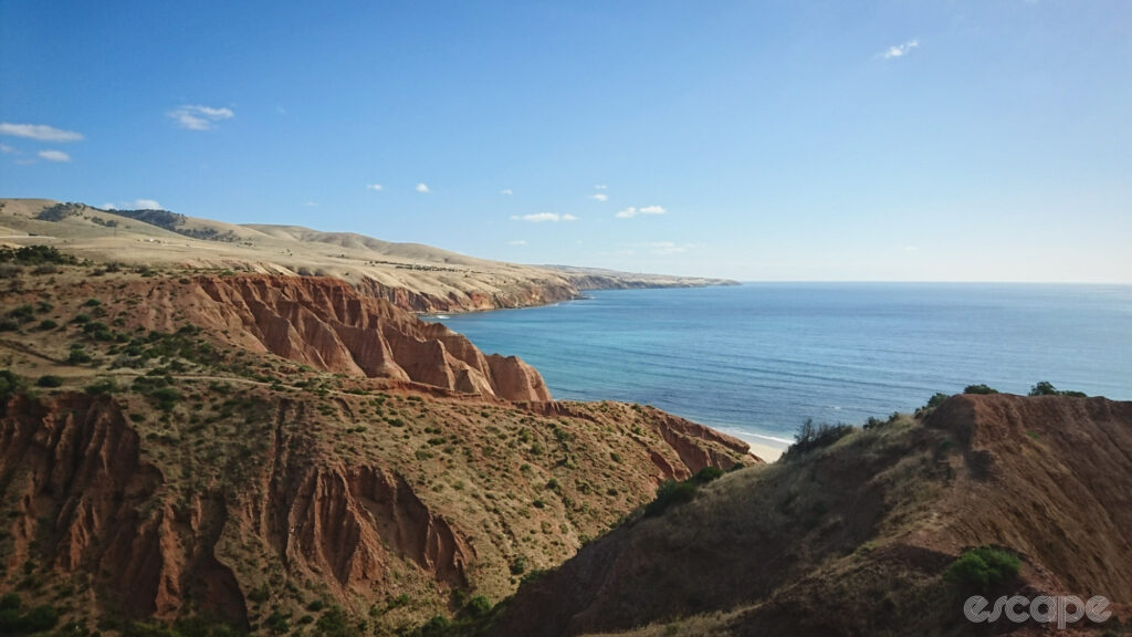 A view along the coast with ochre cliffs leading to blue seas.